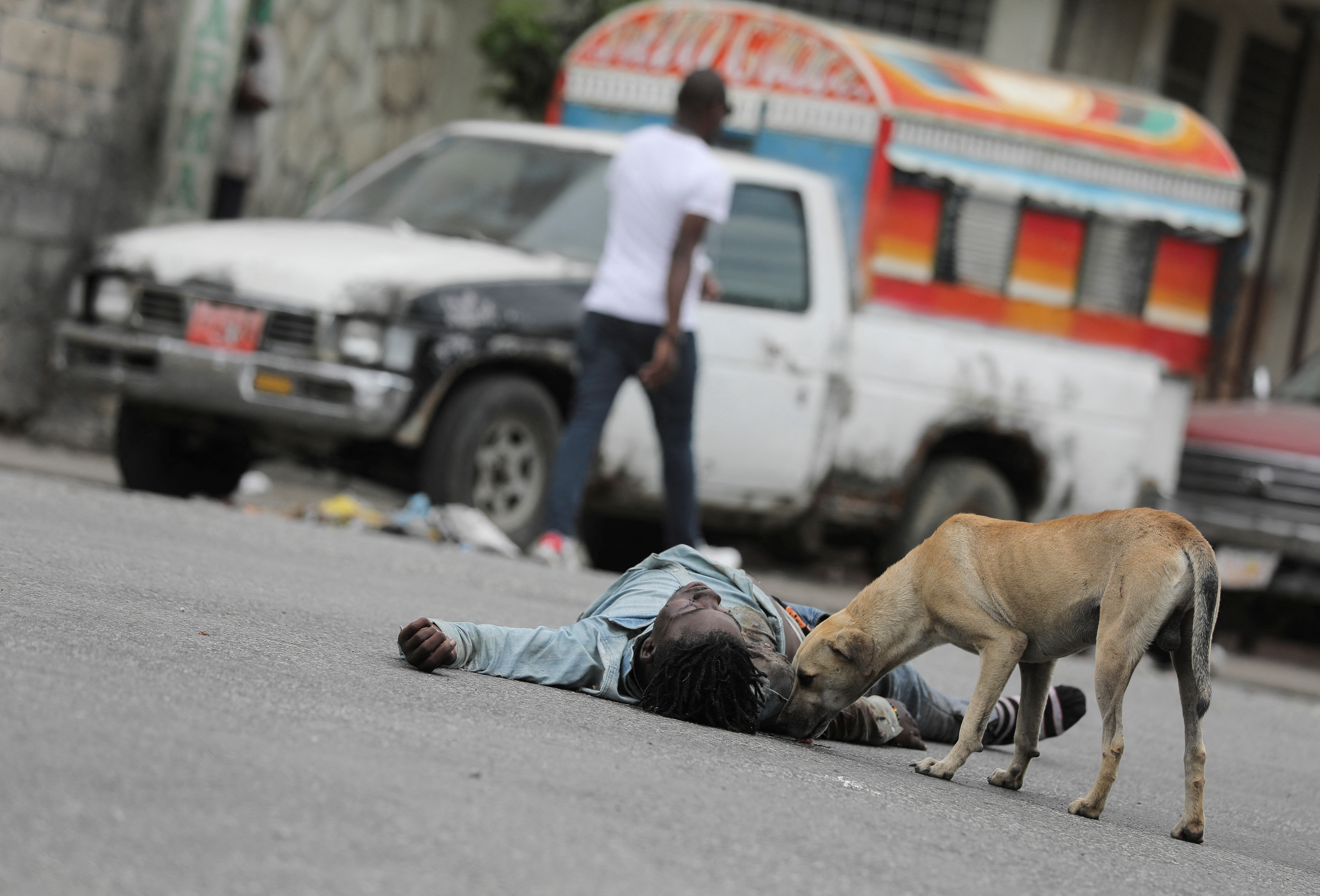 MATERIAL SENSIBLE. Un perro permanece cerca del cadáver de un presunto miembro de una banda, que se cree que murió en enfrentamientos entre residentes y miembros de la banda (REUTERS/Ralph Tedy Erol)