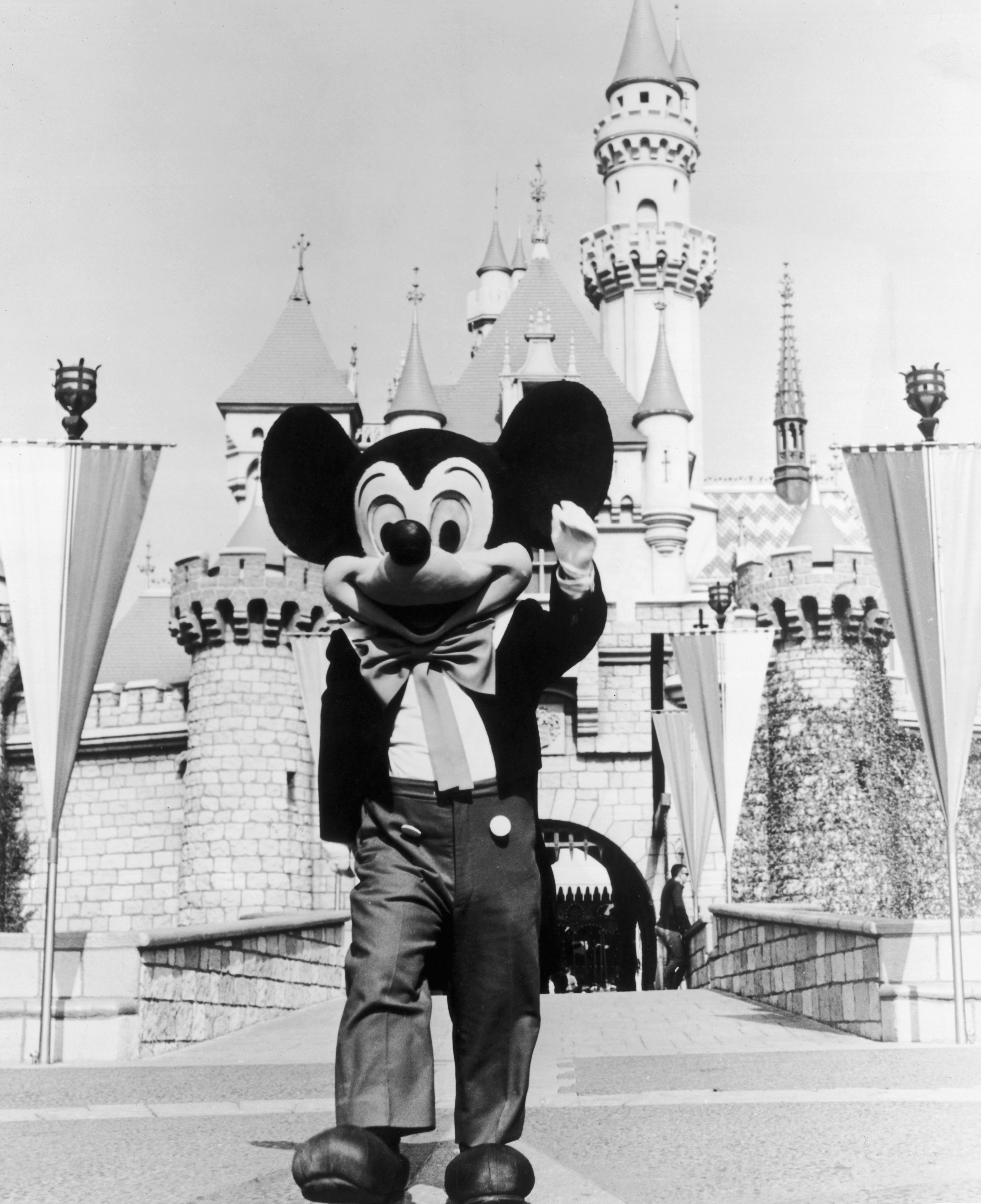 Alrededor de 1955: Una persona con un disfraz de Mickey Mouse en la puerta del Reino Mágico en el parque temático Disneyland, Anaheim, California. (Foto de Hulton Archive/Getty Images)