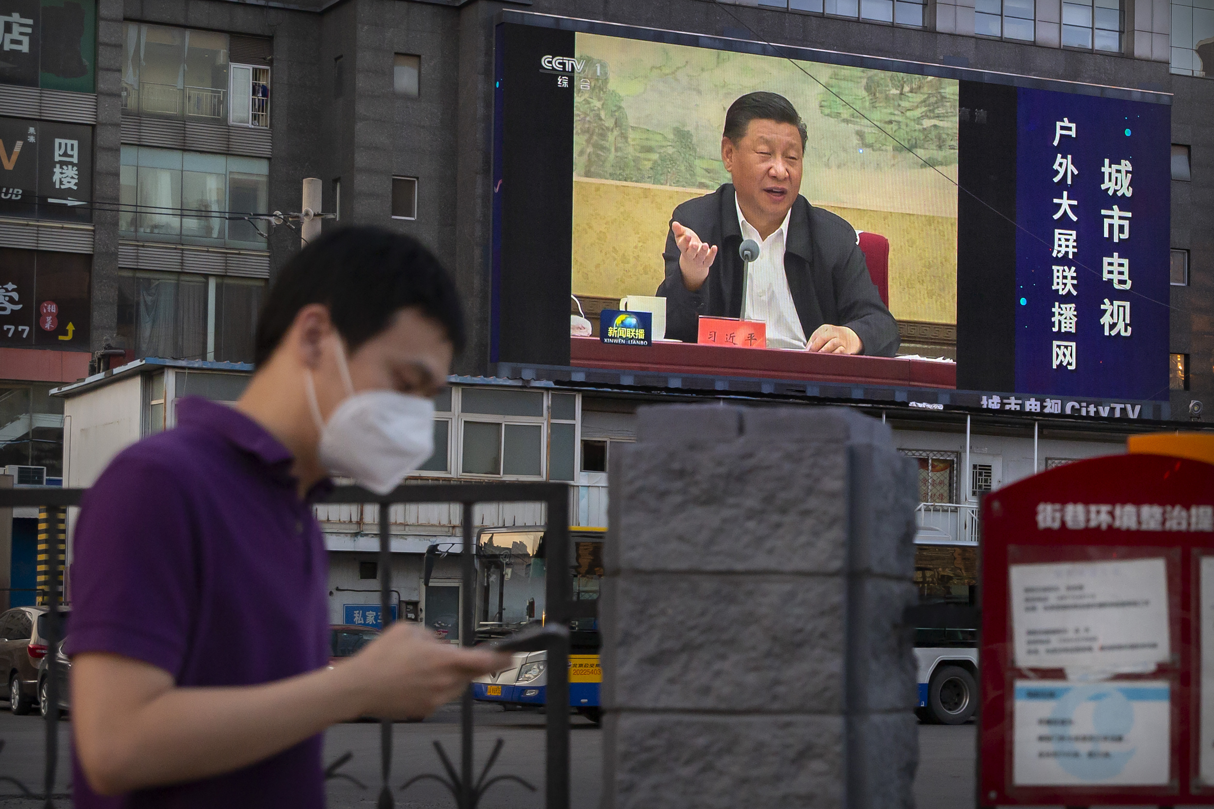 Un joven en Beijing con la imagen del presidente Xi Jinping de fondo. (AP Photo/Mark Schiefelbein)