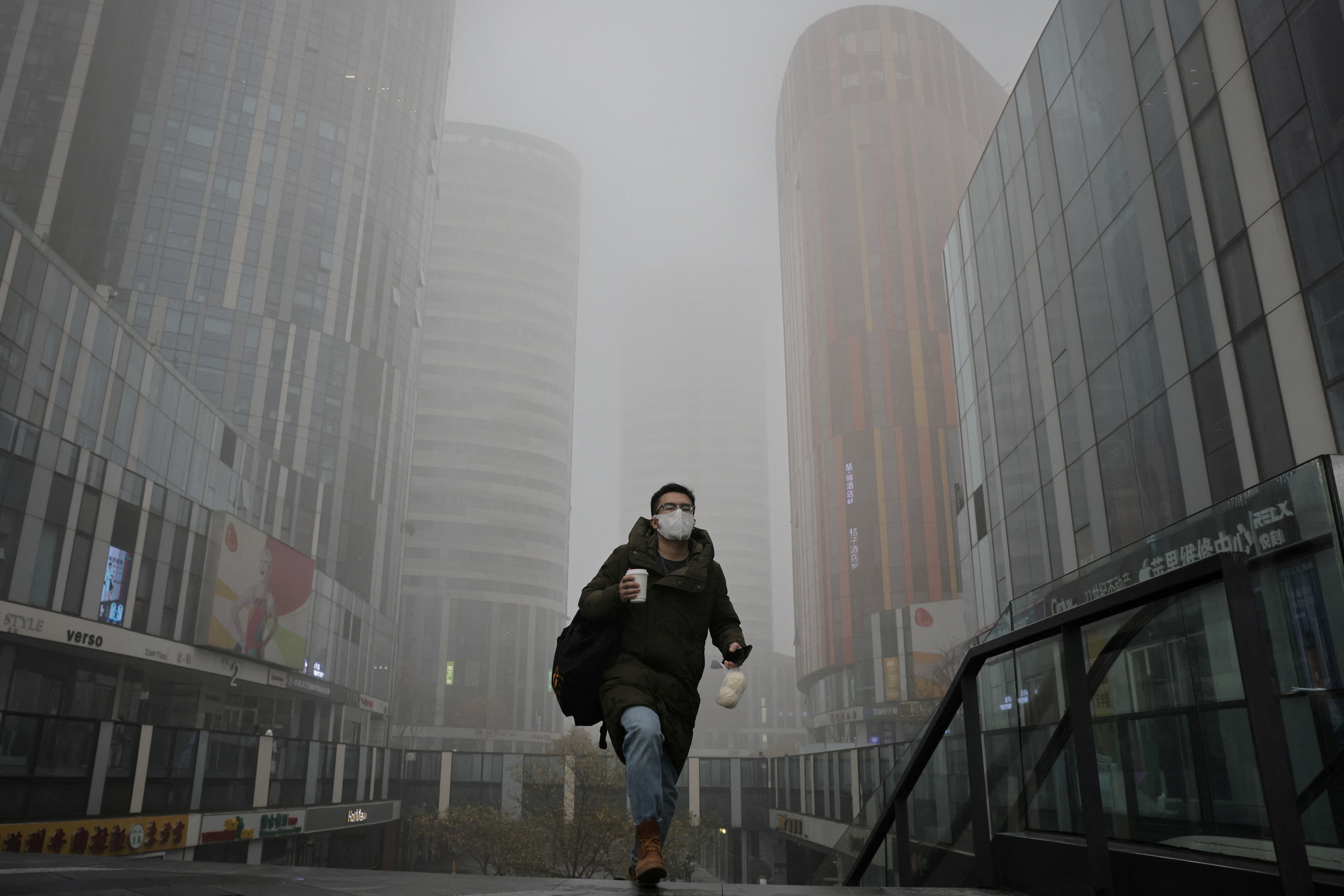 Un hombre camina en una zona comercial de Beijing (Reuters)