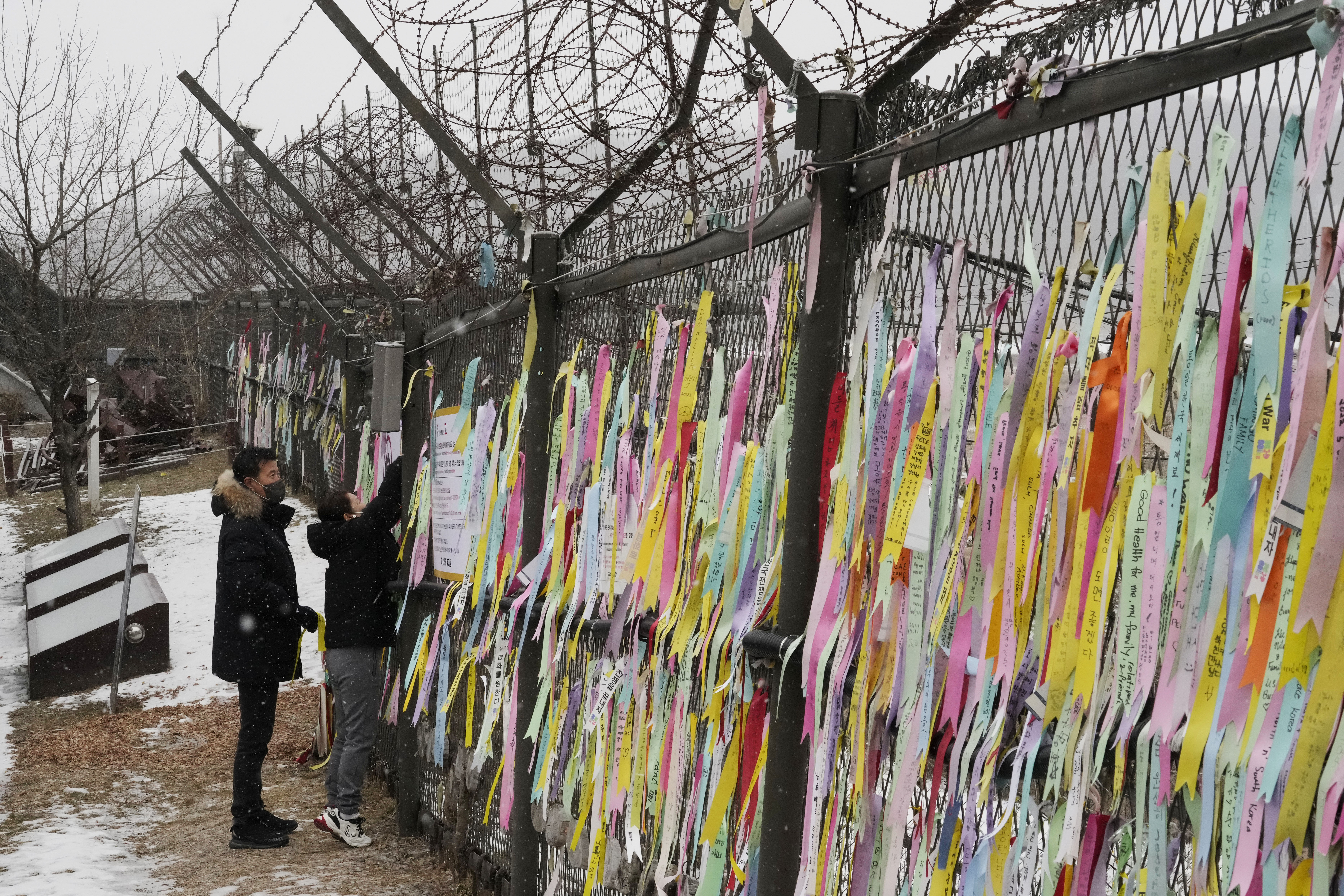 A woman hangs a ribbon wishing for the reunification of the two Koreas on a fence during a visit to the Imjingak Pavilion near the border with the North to celebrate the Lunar New Year in Paju, South Korea, Sunday, Jan. 22, 2023. (AP Photo/Ahn Young-joon)