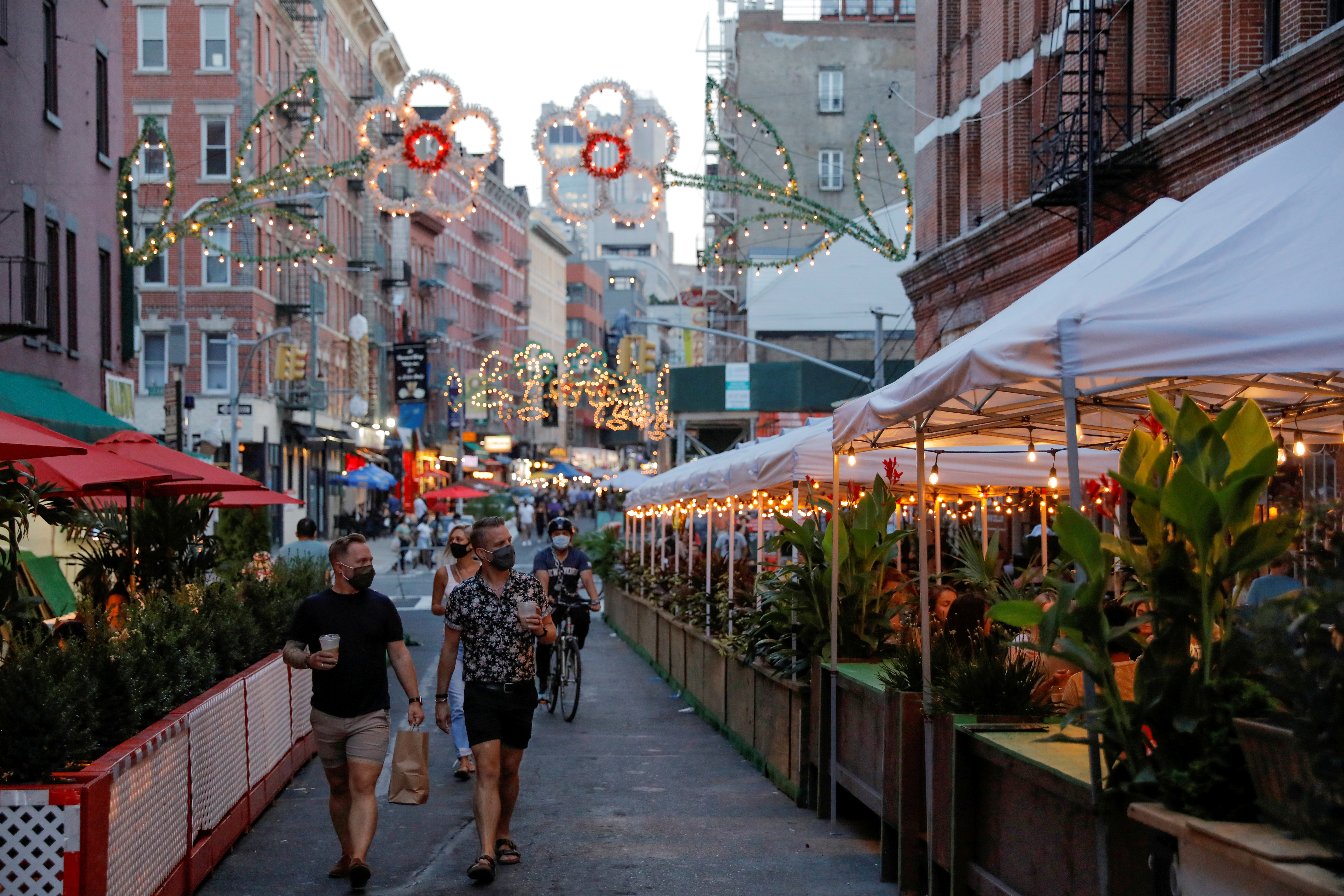 Personas caminan por una calle con restaurantes en la ciudad de Nueva York. A partir del 30 podrán volver a prestar servicios dentro de sus establecimientos. Foto: REUTERS/Andrew Kelly     