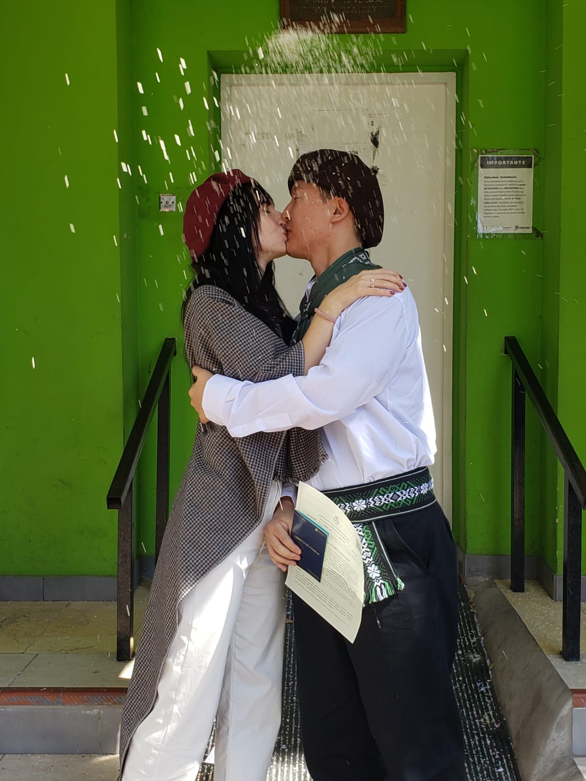El beso de los novios mientras sostienen la libreta azul, oficialmente como marido y mujer con lluvia de arroz incluida