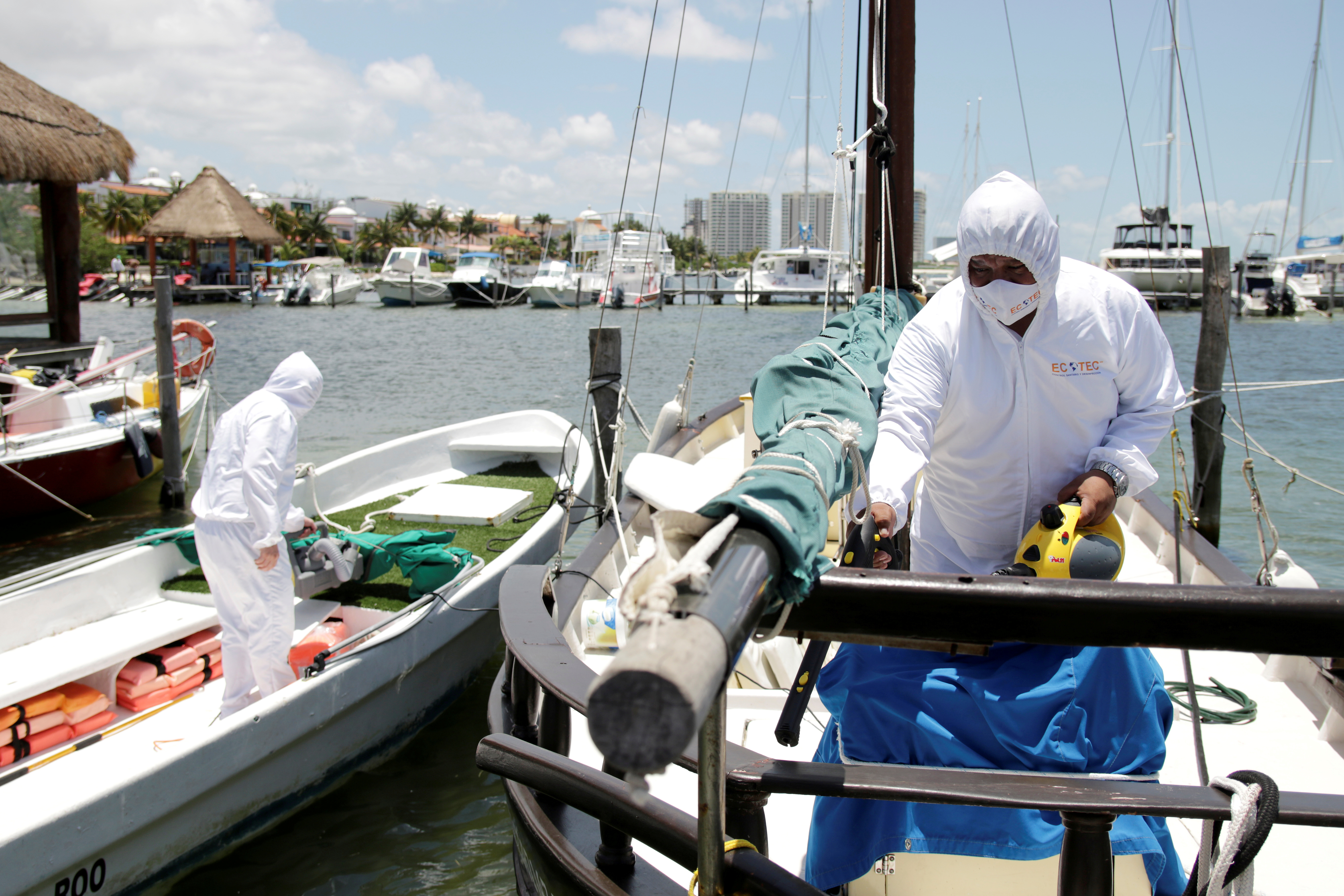Los empleados de una empresa privada desinfectan los barcos en un puerto deportivo después de que las autoridades locales impusieron estrictas medidas sanitarias para reabrir gradualmente a pesar de la pandemia de la enfermedad por coronavirus (COVID-19), en Cancún, México, 10 de junio de 2020. Fotografía tomada el 10 de junio de 2020. Foto: Reuters.