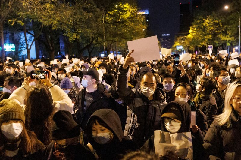 Personas sostienen hojas de papel blanco en protesta por las restricciones del COVID en Beijing (Reuters)