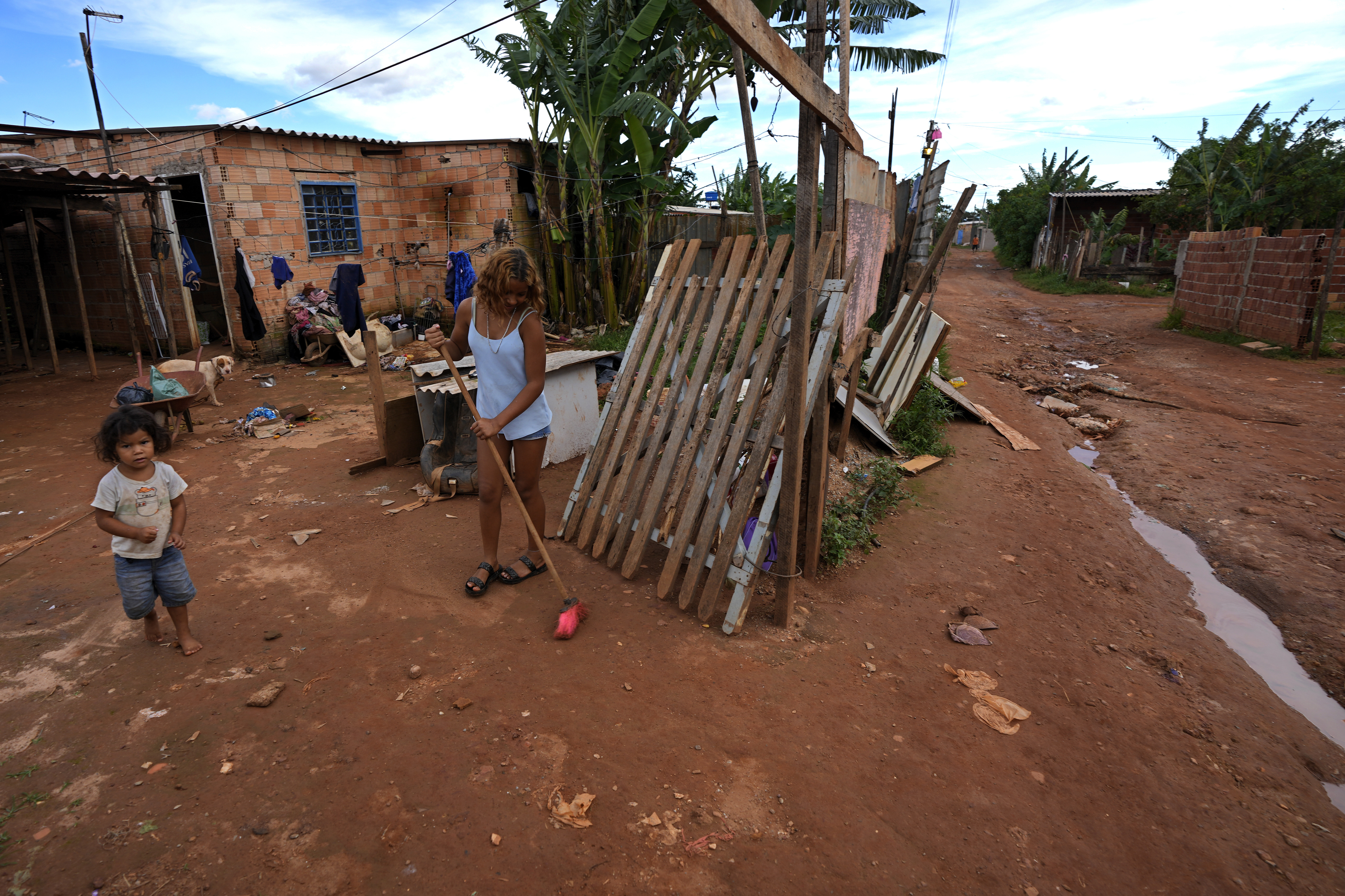 Una mujer barre el camino de tierra afuera de su casa en la favela Sol Nascente  (AP Foto/Eraldo Peres)