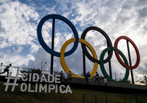 Youngsters walk past the Olympic rings at Madureira Park, the third largest park in Rio de Janeiro, Brazil, on July 1, 2015, 400 days ahead of the Rio 2016 Olympic games. The 12-meter-high symbol was shipped from Great Britain after having decorated the Tyne Bridge in Newcastle during the 2012 London Olympic Games. AFP PHOTO / YASUYOSHI CHIBA        (Photo credit should read YASUYOSHI CHIBA/AFP/Getty Images)