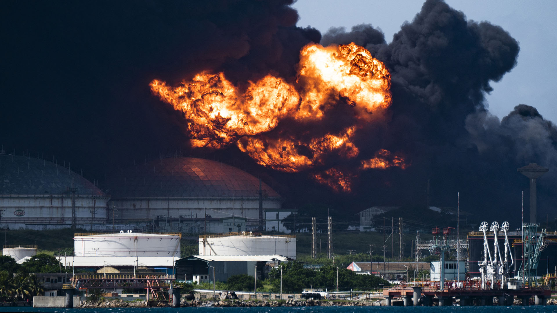 View of the massive fire at a fuel depot, sparked overnight by a lightning strike, in Matanzas, in western Cuba, taken on August 6, 2022. - Cuba asked for help Saturday to contain the massive fire that left 77 people injured and 17 firefighters missing. Some 800 people have been evacuated from the area. (Photo by Yamil LAGE / AFP)