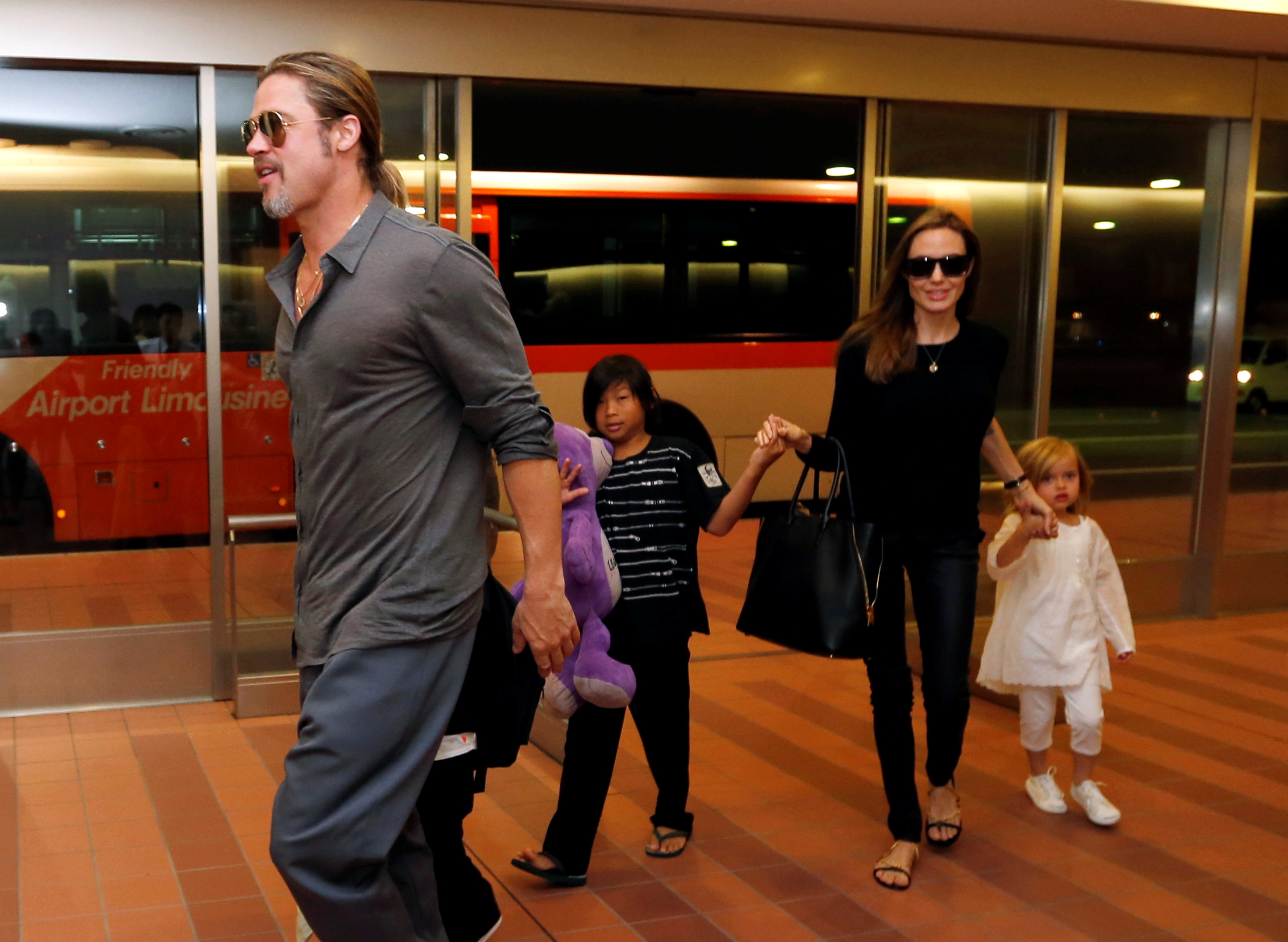 PHOTO DE DOSSIER : Pitt et Jolie arrivent avec leurs enfants Knox, Vivienne et Pax à l'aéroport international de Haneda à Tokyo, Japon, le 28 juillet 2013 (REUTERS/Issei Kato)