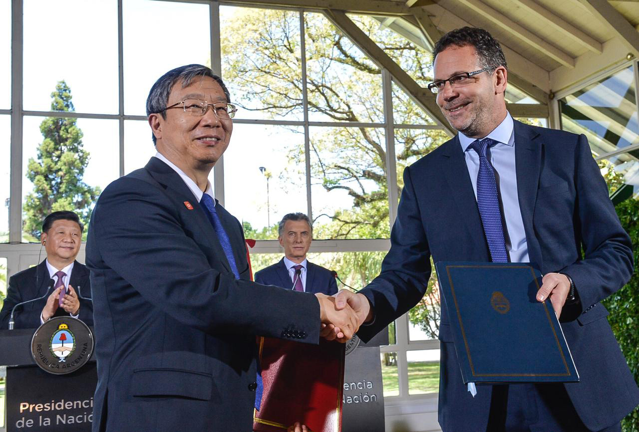 En 2018, durante la Cumbre del G20 en Buenos Aires, Sandlerís firmó con Yi Gang, un "acuerdo suplementario". Detrás de ellos puede observarse, en Olivos, al presidente chino, Xi Jinping, y a Mauricio Macri