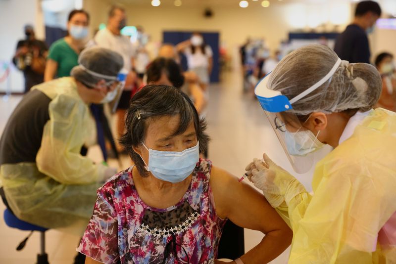 Una trabajadora sanitaria administra una dosis de la vacuna de AstraZeneca contra el COVID-19 a una mujer durante una sesión de vacunación para personas mayores de 75 años, en un estadio de la ciudad de Nuevo Taipéi, Taiwán,( REUTERS/Ann Wang)