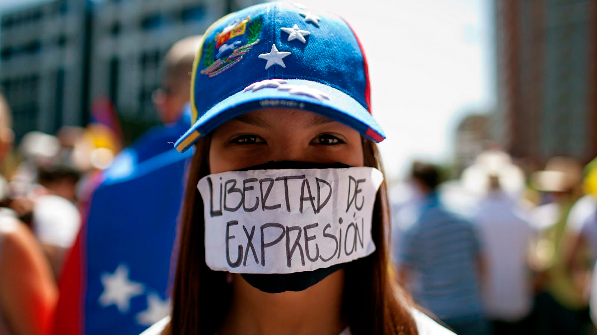 Una joven se tapa la boca con un cartel que reclama "libertad de expresión" en Venezuela (Archivo)