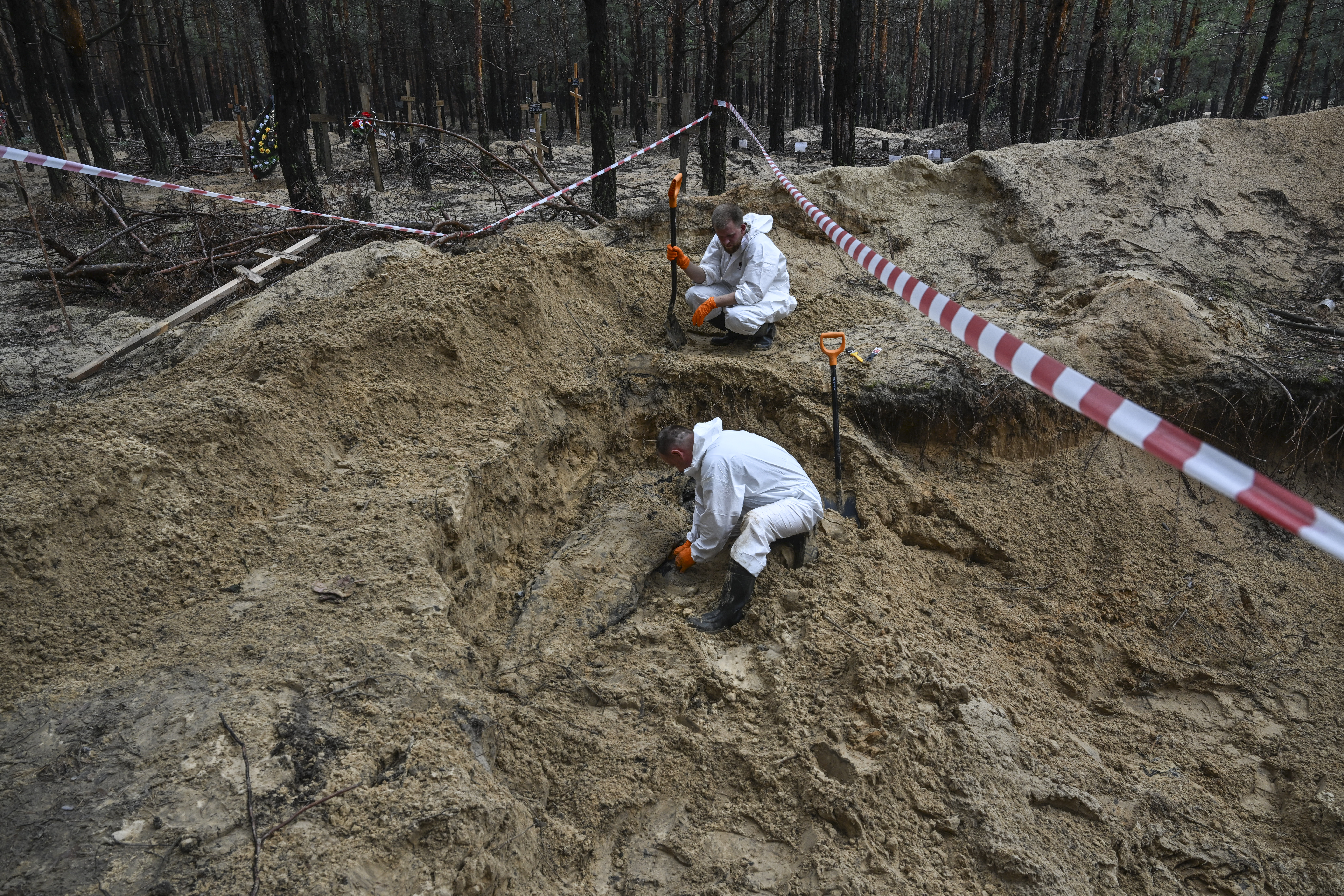 Los operarios desentierran cuerpos hallados en uan fosa común en Izium, una zona recientemente liberada tras la ocupación rusa