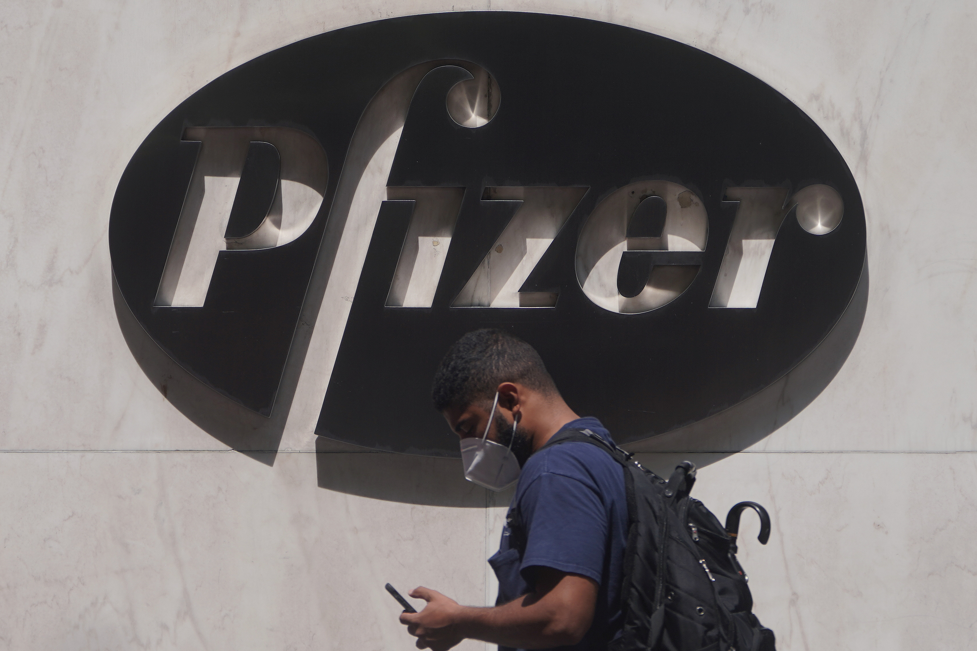 Un hombre pasa por delante del logo de la compañía farmacéutica Pfizer. Foto: REUTERS/Carlo Allegri
