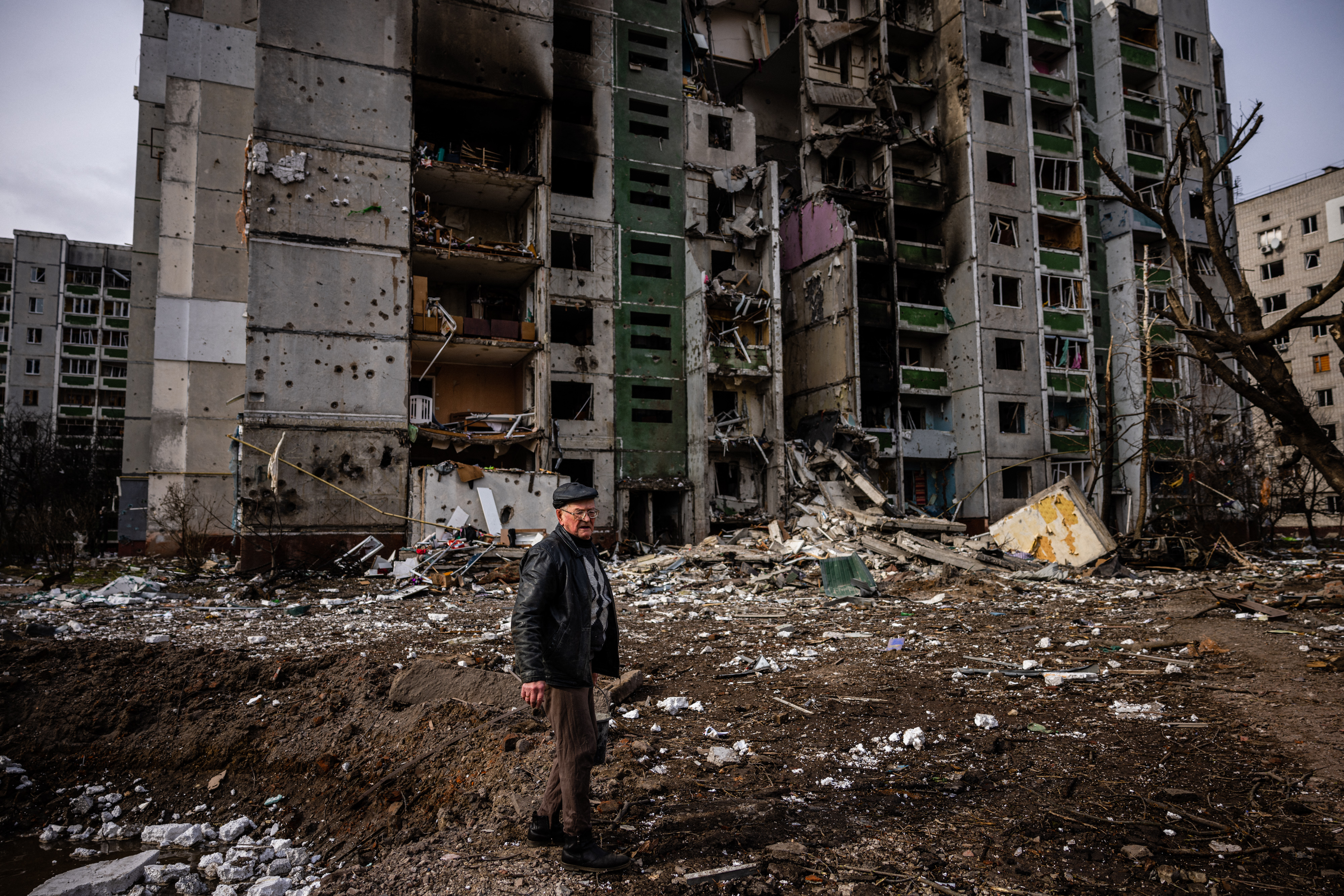 A man stands in front of a residential building damaged in yesterday's shelling in the city of Chernihiv on March 4, 2022. - Fourty-seven people died on March 3 when Russian forces hit residential areas, including schools and a high-rise apartment building, in the northern Ukrainian city of Chernihiv, officials said. (Photo by Dimitar DILKOFF / AFP)