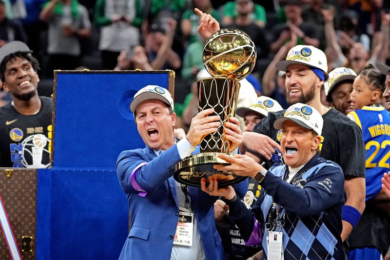 Los propietarios de los Golden State Warriors, Joseph Lacob y Peter Guber, celebran con el trofeo de campeón Larry O'Brien después de que los Golden State Warriors vencieran a los Boston Celtics en el sexto partido de las Finales de la NBA de 2022