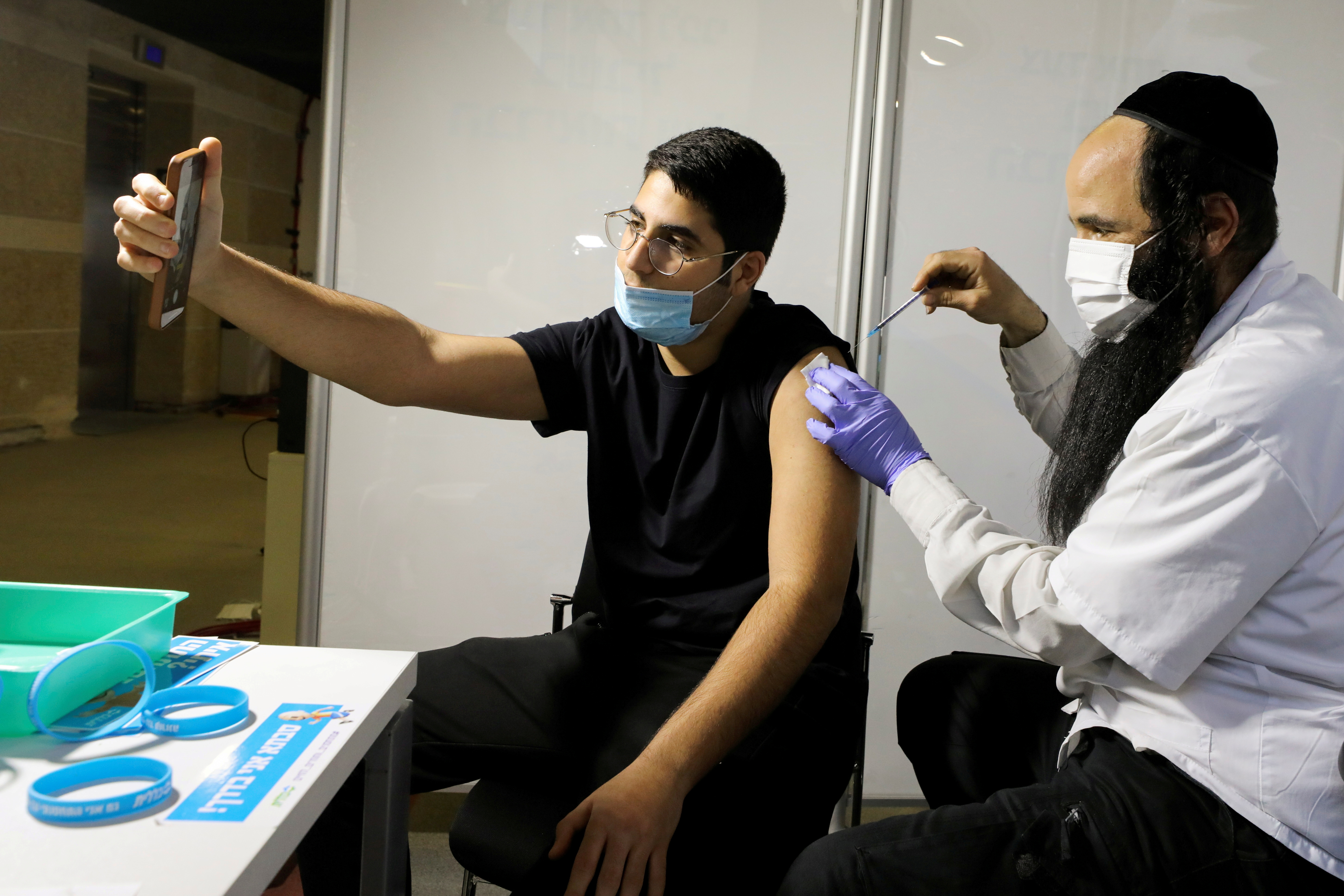 Un joven recibe una vacuna contra la enfermedad del coronavirus (COVID-19) en un centro de vacunación temporal de la organización de mantenimiento de la salud (HMO) de Clalit, en un estadio deportivo en Jerusalén (Reuters)