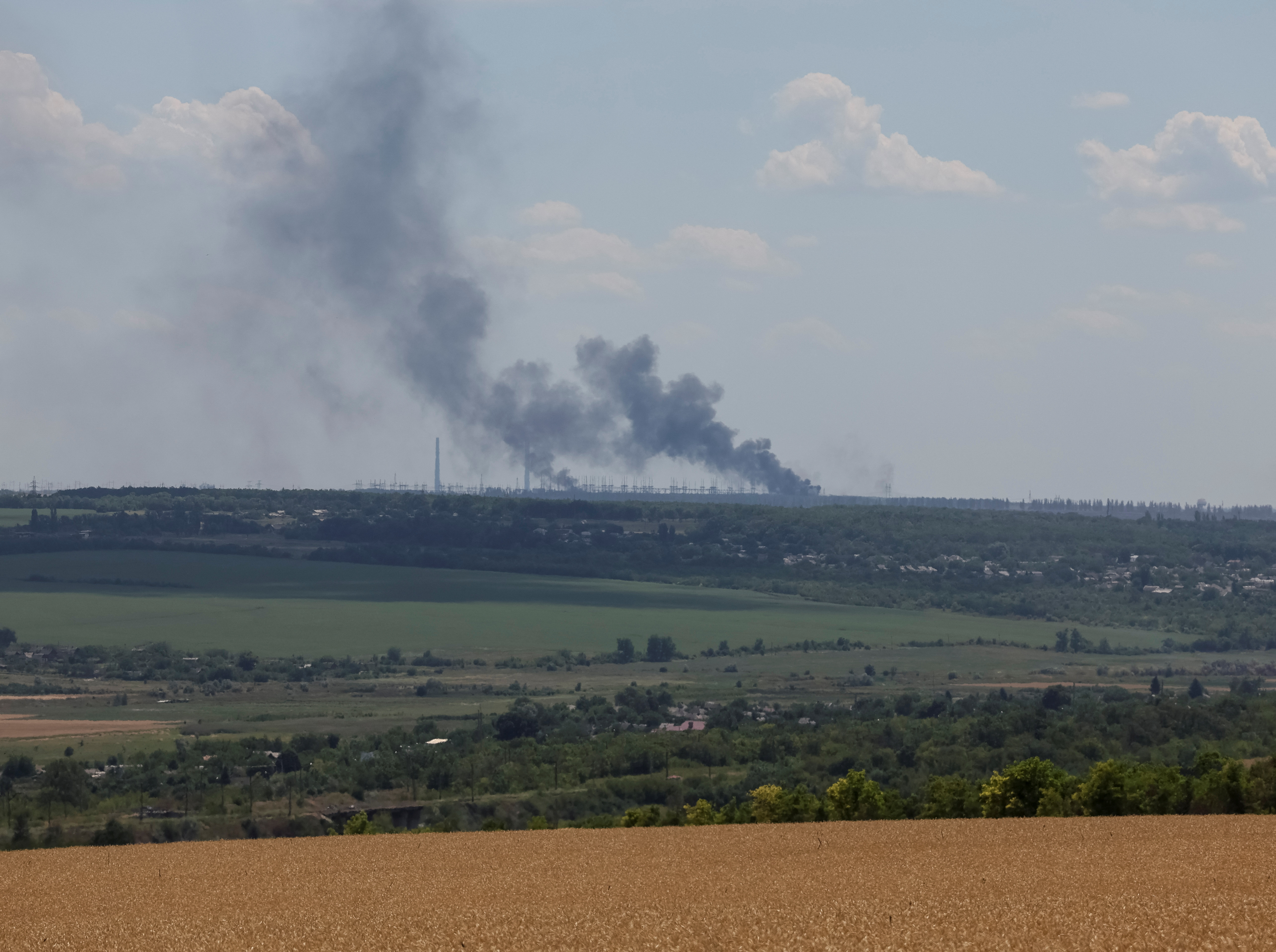 La central térmica de Vuhlehirsk arde en la distancia tras un bombardeo, en medio del ataque de Rusia a Ucrania, cerca de la ciudad de Svitlodarsk, región de Donetsk, Ucrania 13 de julio de 2022. REUTERS/Gleb Garanich