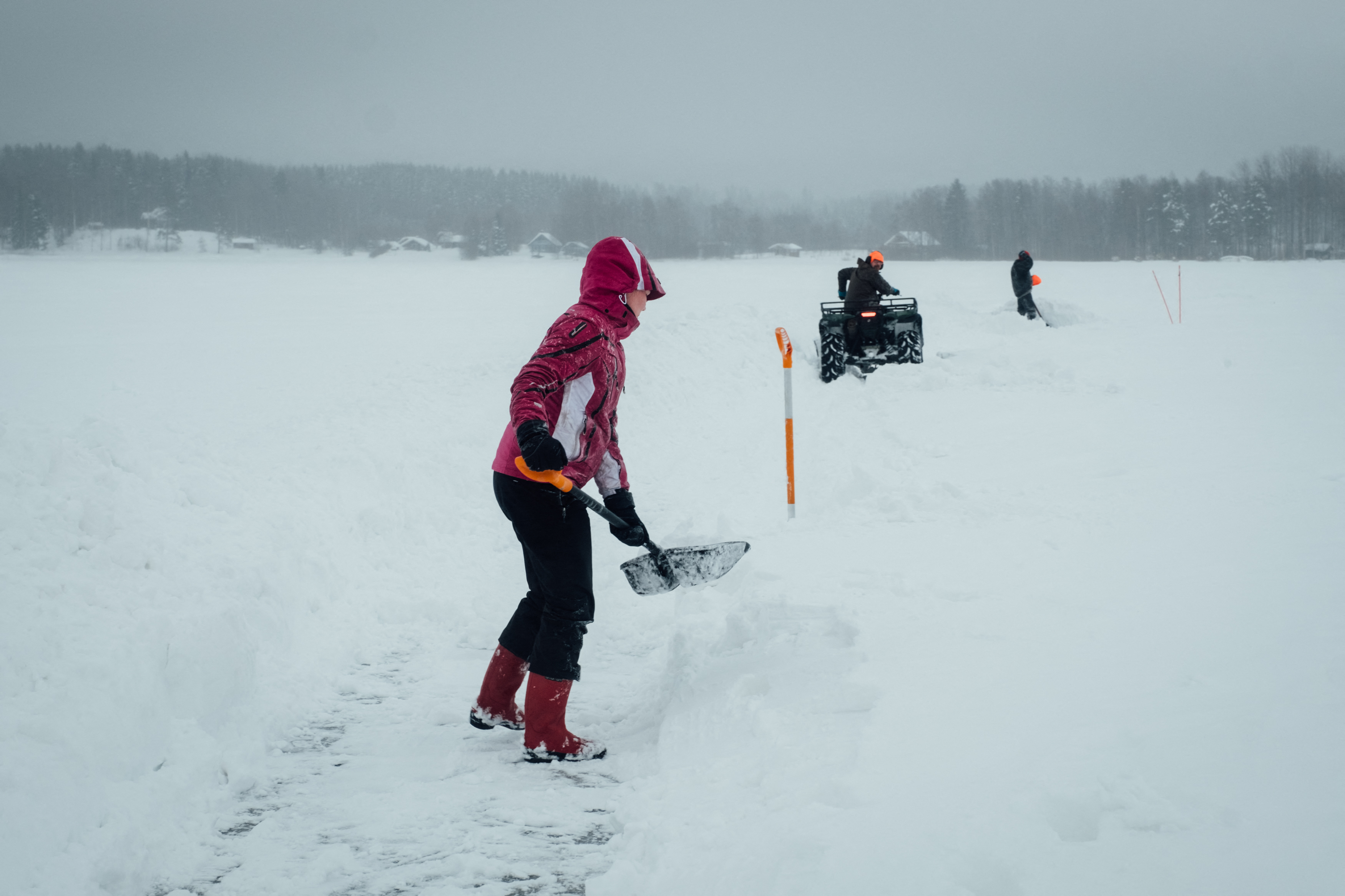 La gente quita la nieve a lo largo del perímetro de un carrusel de hielo que está en construcción para un intento de récord mundial en el lago congelado. (Alessandro RAMPAZZO / AFP)