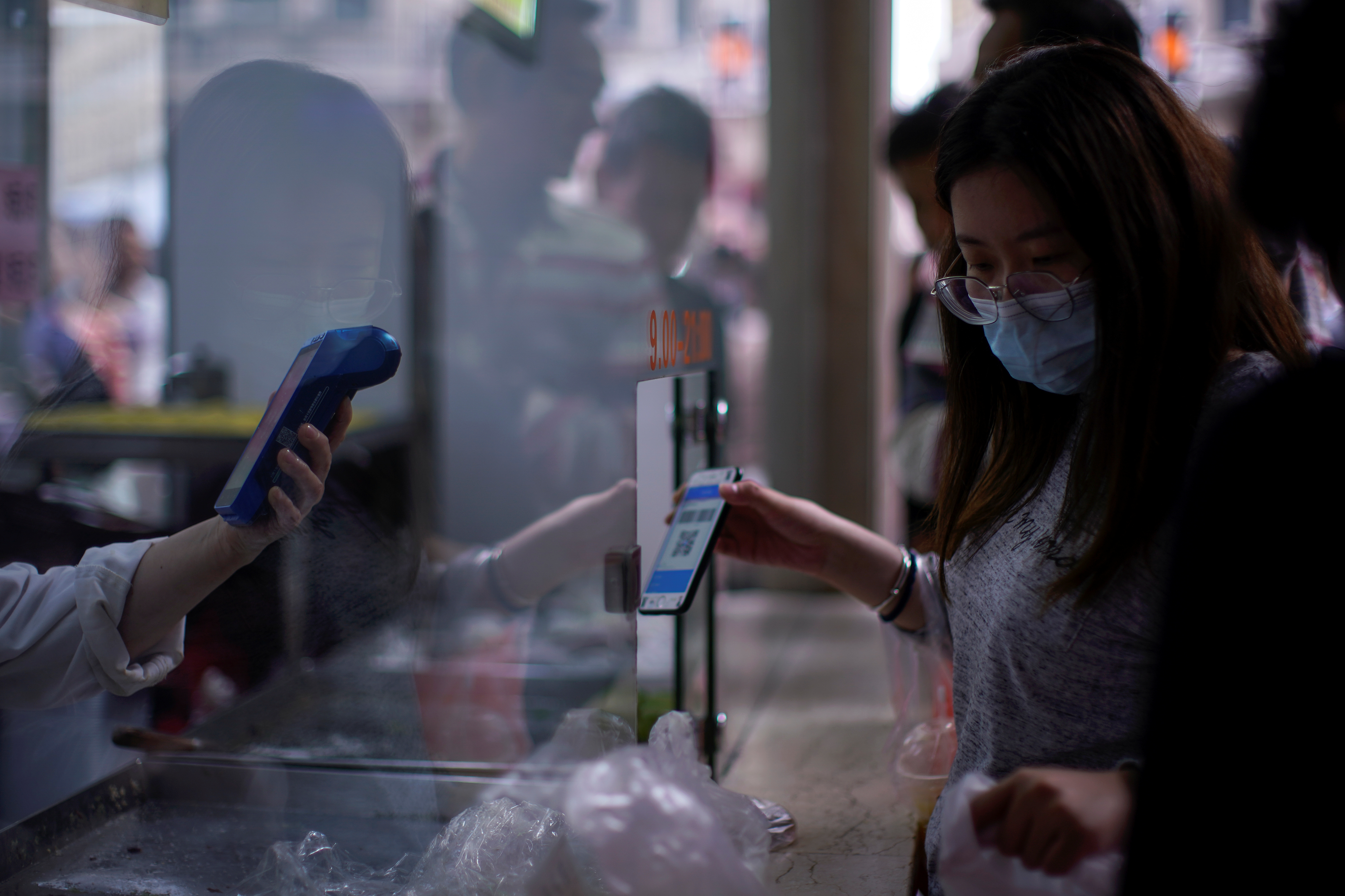 A woman gets her phone's QR code of the digital payment services scanned at a food shop, following the coronavirus disease (COVID-19) outbreak, in Shanghai, China October 10, 2020. REUTERS/Aly Song