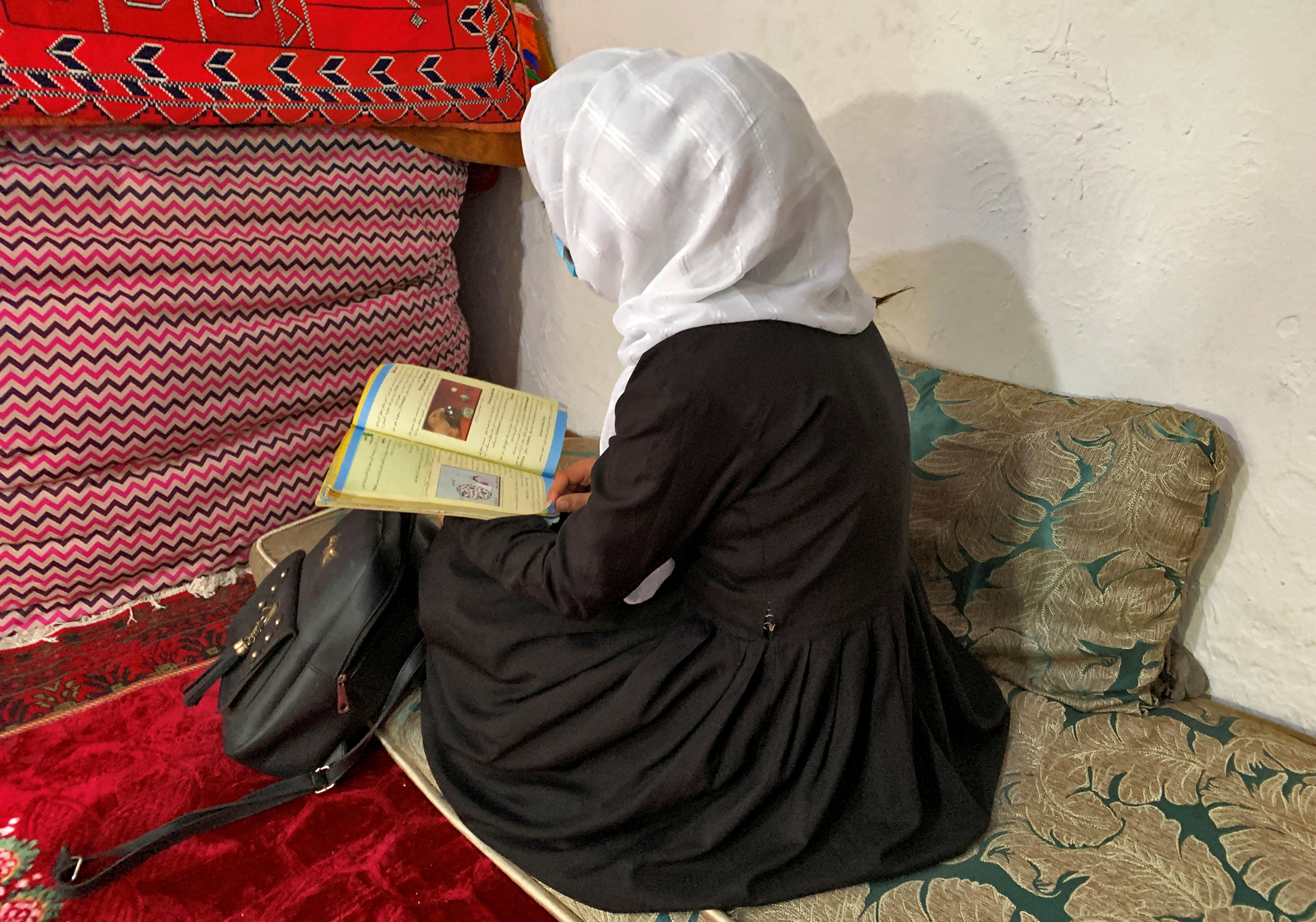 Dal file: una studentessa afgana legge il suo libro all'interno di una casa a Kabul.  Fotografia: Charlotte Greenfield/Reuters