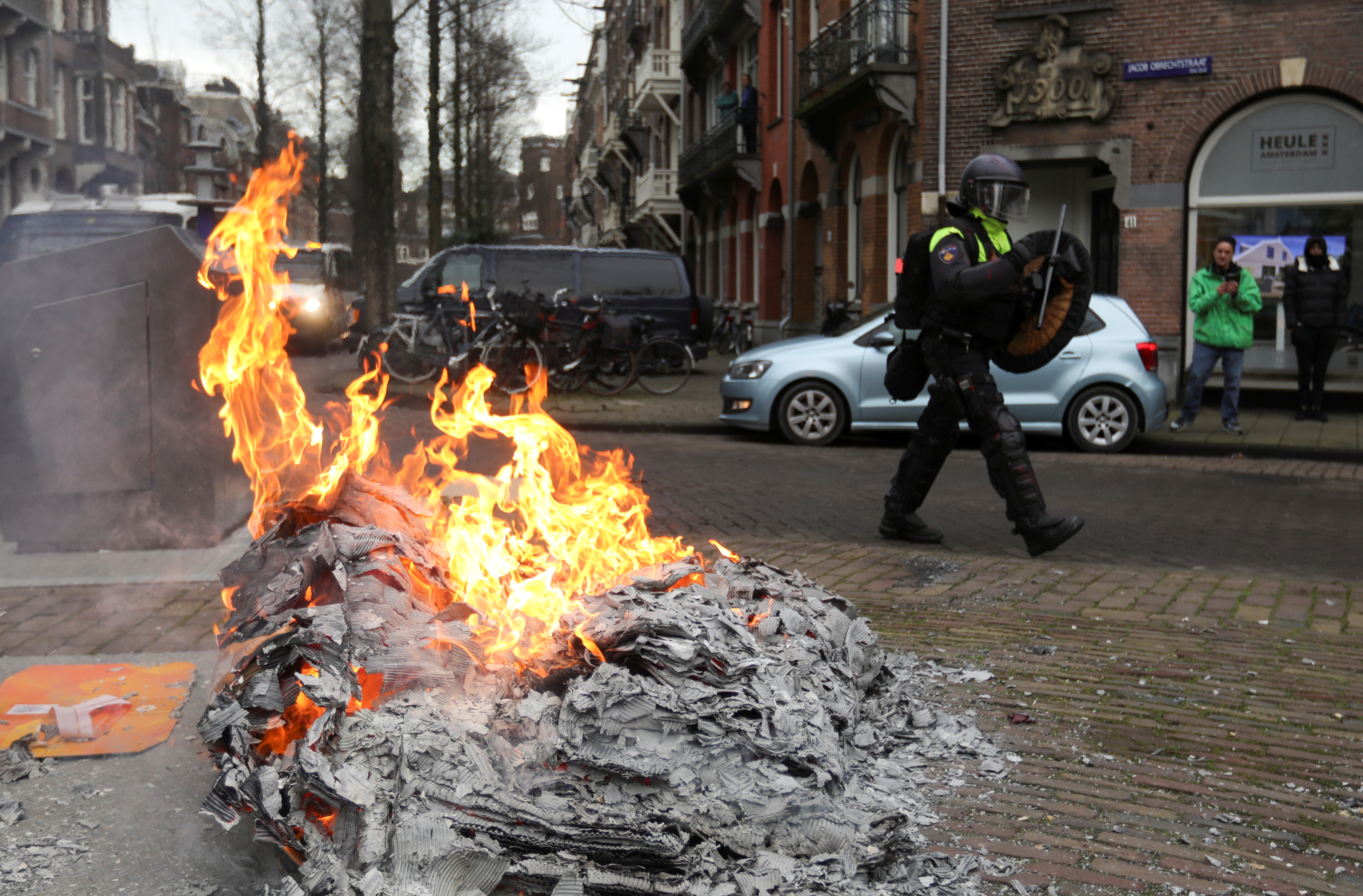 Un agente de policía camina cerca de una hoguera durante una protesta contra las restricciones establecidas para frenar la propagación del COVID-19 en Ámsterdam, el 24 de enero de 2021 (REUTERS/Eva Plevier)
