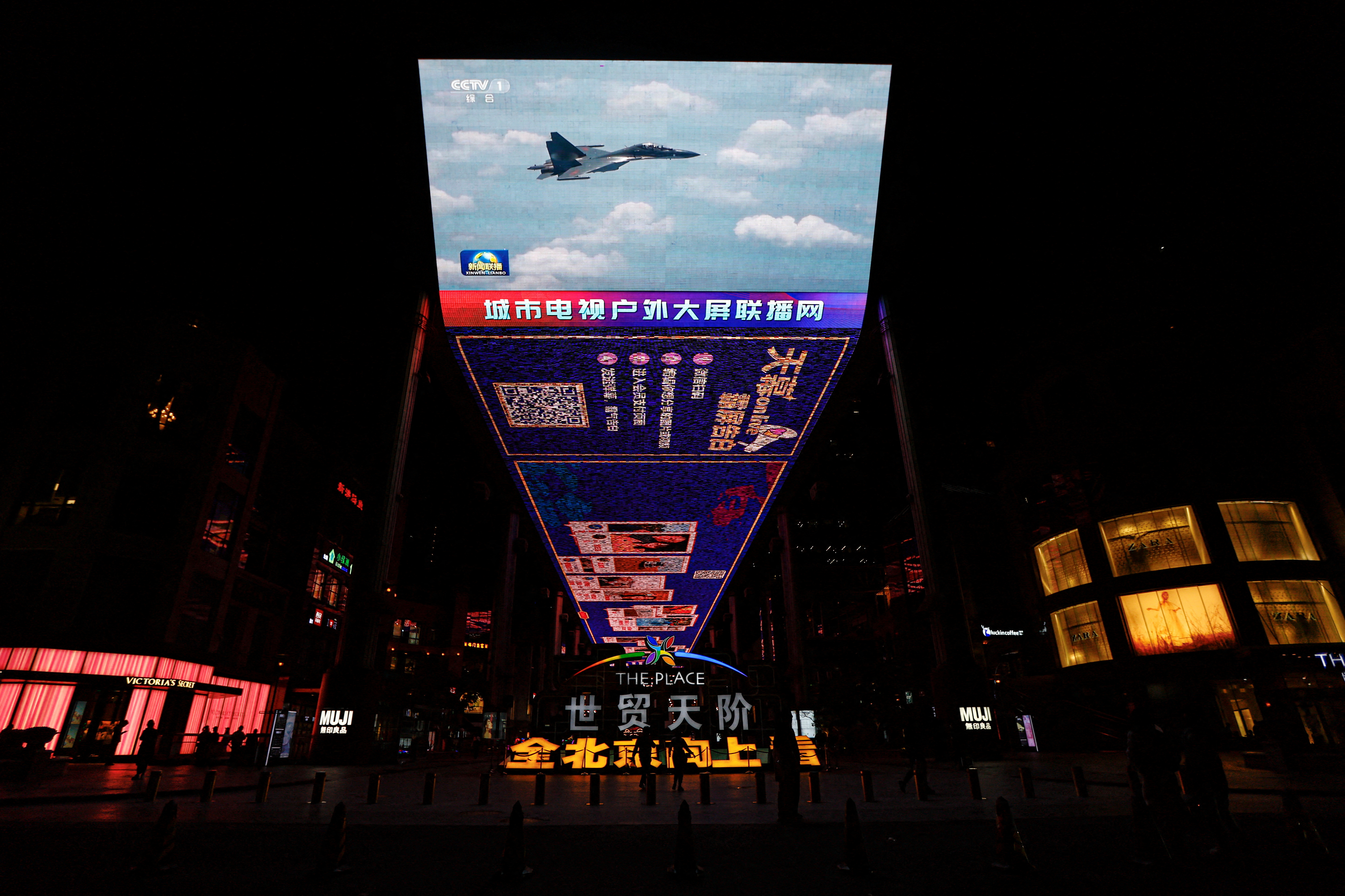 Una pantalla gigante emite imágenes de un caza de las Fuerzas Aéreas del Mando del Teatro Oriental del Ejército Popular de Liberación de China (EPL) que participa en unas patrullas de preparación para el combate y en unos ejercicios "Espada Conjunta" en torno a Taiwán, en una zona comercial de Pekín, China (REUTERS/Tingshu Wang)