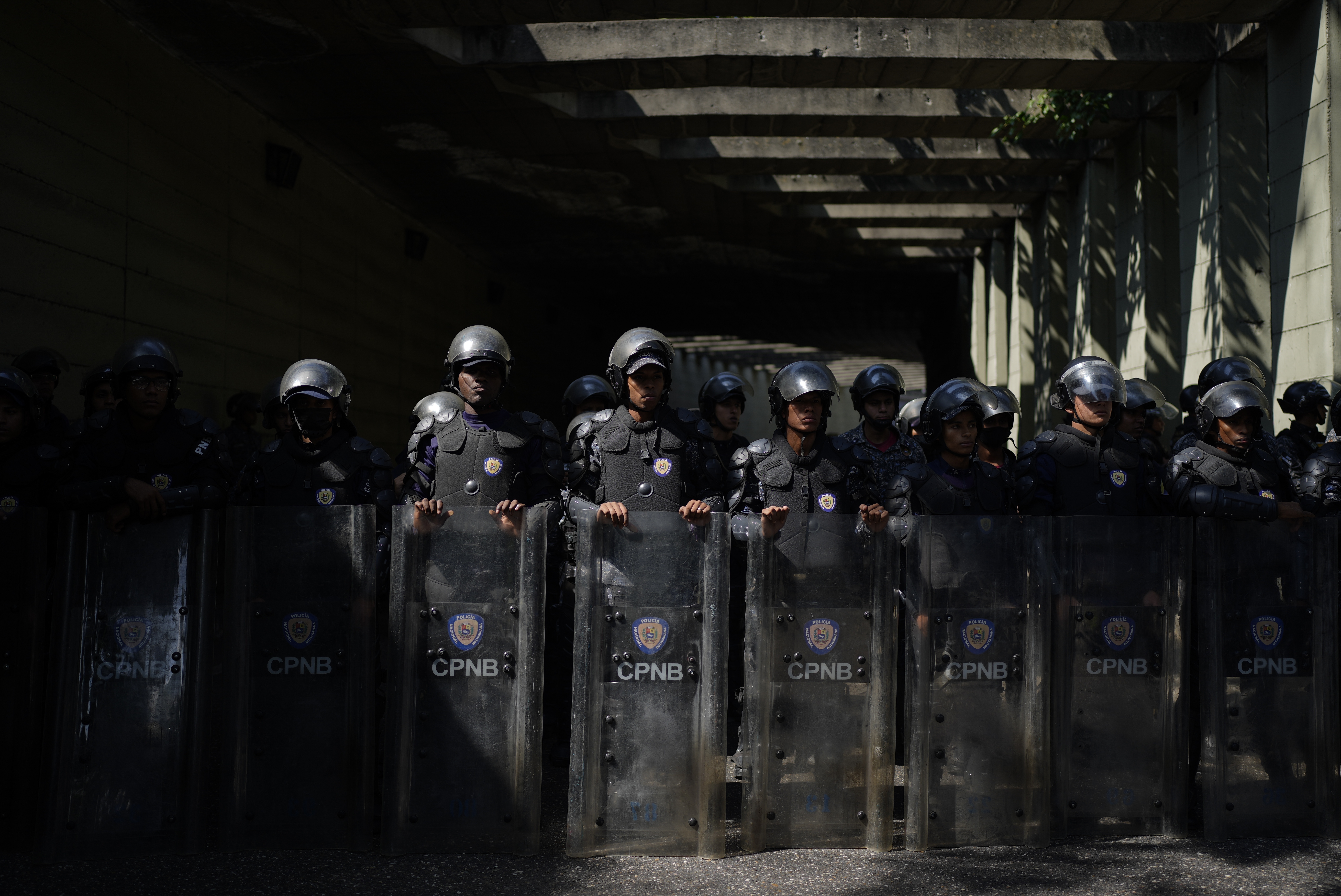 La policía hace guardia en los límites de una marcha de profesores, funcionarios y pensionistas para pedir mayores salarios y pensiones, así como el pago total de sus beneficios, en Caracas, Venezuela, el lunes 16 de enero de 2023 (AP Foto/Ariana Cubillos)
