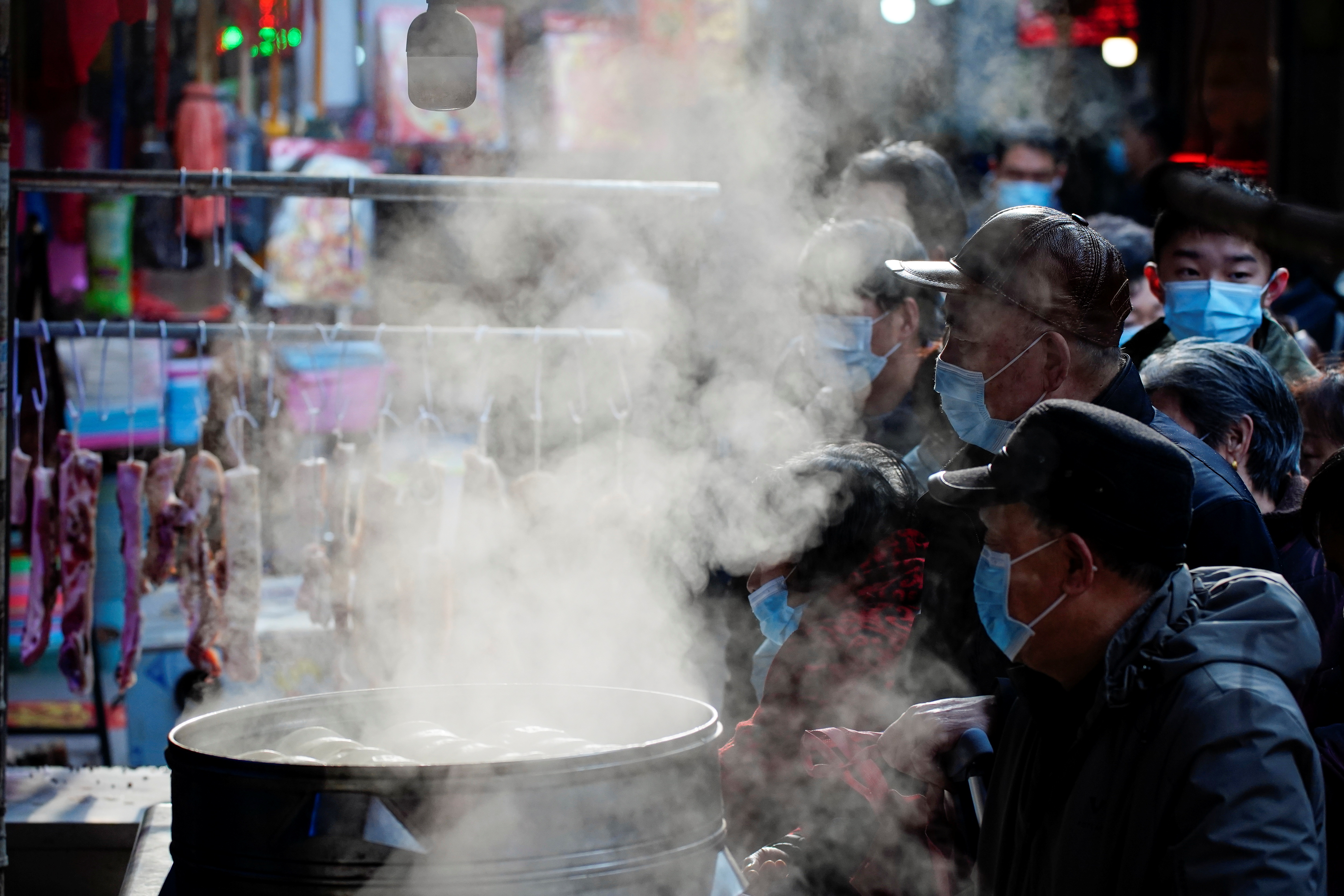 FOTO DE ARCHIVO: Personas con mascarillas esperan para comprar comida en un puesto de comida al vapor en un mercado callejero, tras un brote de la enfermedad del coronavirus (COVID-19) en Wuhan, provincia de Hubei, China 8 de febrero de 2021 (Reuters)