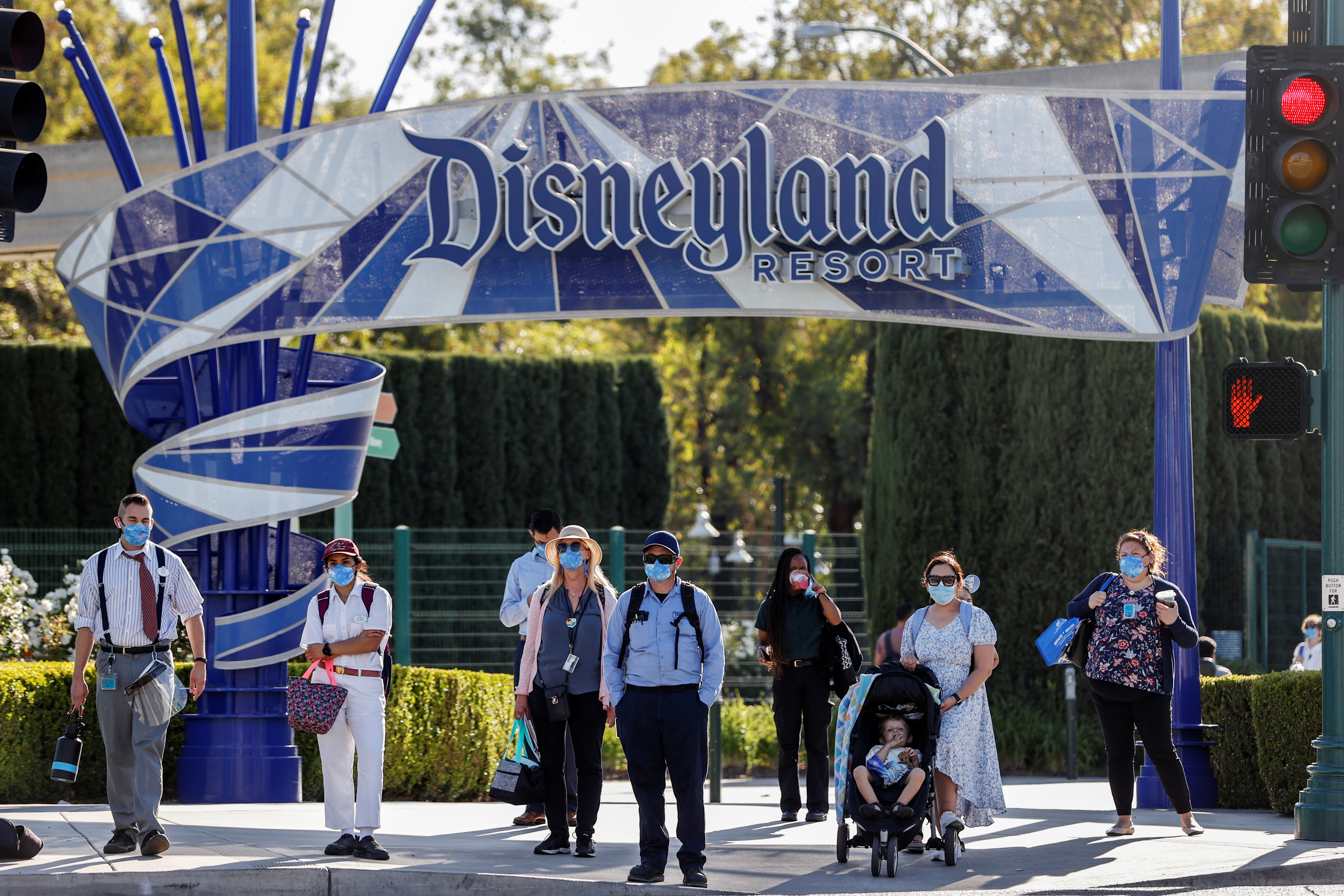 La gente espera en un paso de peatones bajo un cartel de Disneyland Resort en el día de reapertura del Parque Disneyland y Disney California Adventure en Anaheim, California REUTERS/Mario Anzuoni