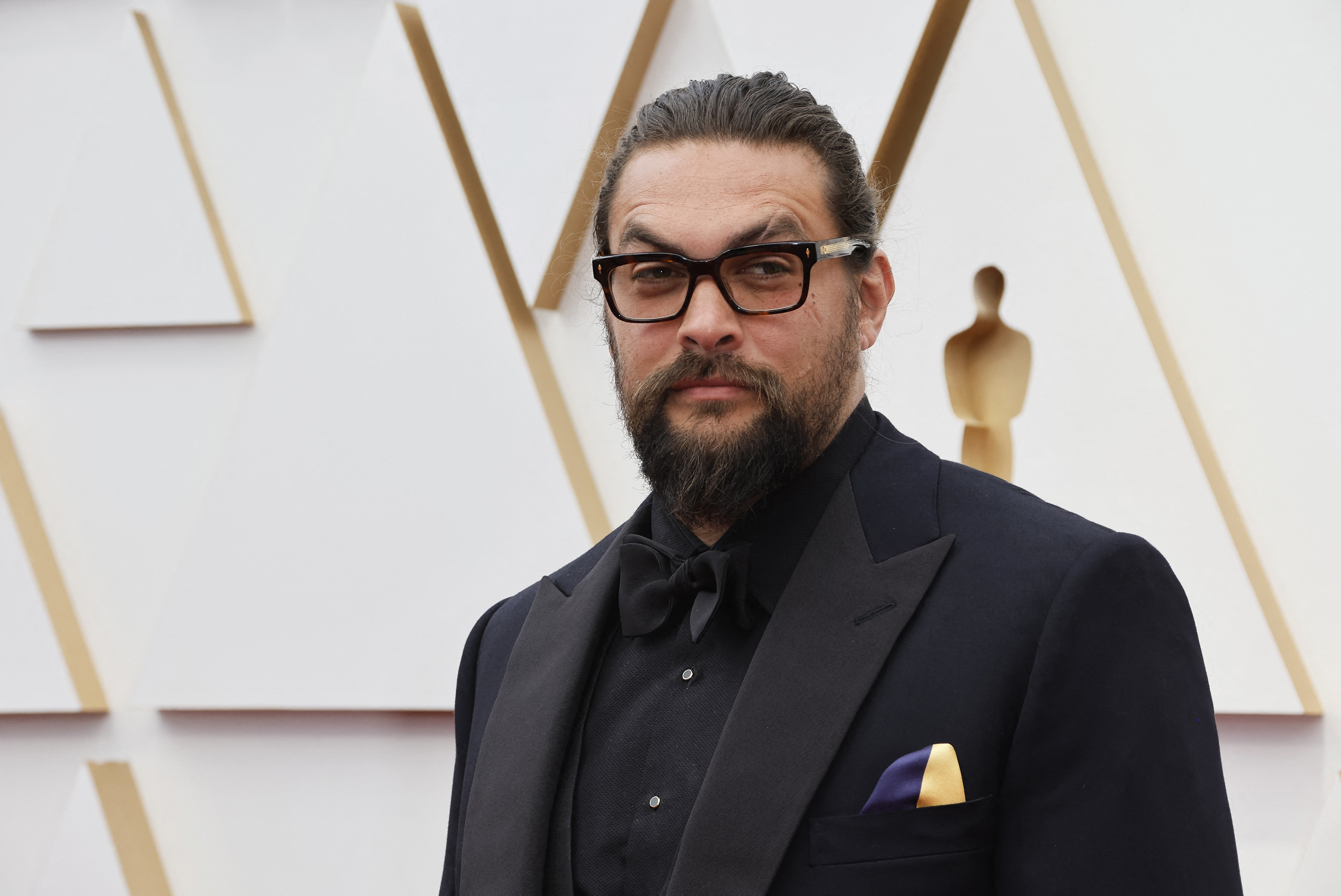 Jason Momoa wears a handkerchief in the colours of the Ukrainian flag in a show of solidarity for Ukraine as Russia's invasion of the country continues as he poses on the red carpet during the Oscars arrivals at the 94th Academy Awards in Hollywood, Los Angeles, California, U.S., March 27, 2022.