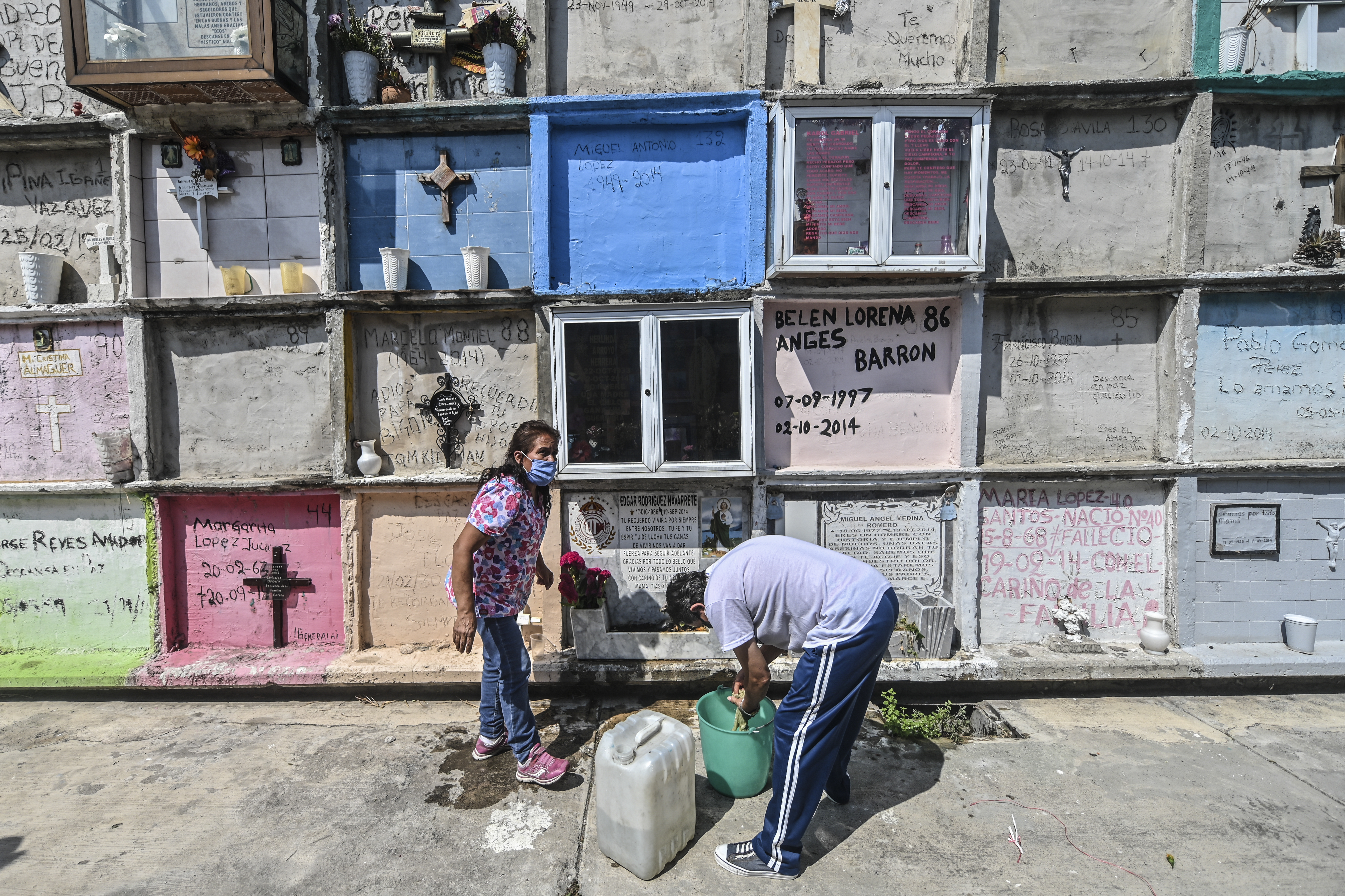 Personas decoran la tumba de un familiar antes del Día de Muertos en el panteón municipal de Nezahualcóyotl, México, el 28 de octubre de 2020, en medio de la pandemia del coronavirus COVID-19.
