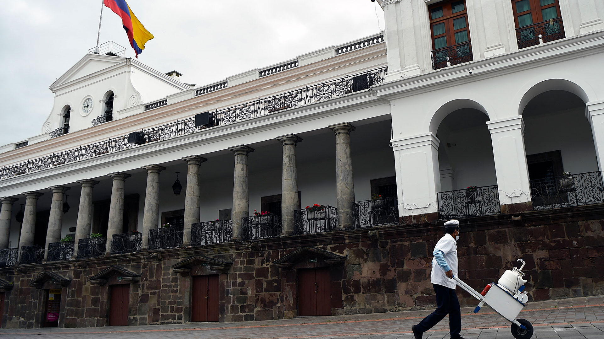 Un vendedor de helados pasa frente al Palacio de Carondelet. El domingo se retiraron las vallas del Centro Histórico. (AFP)