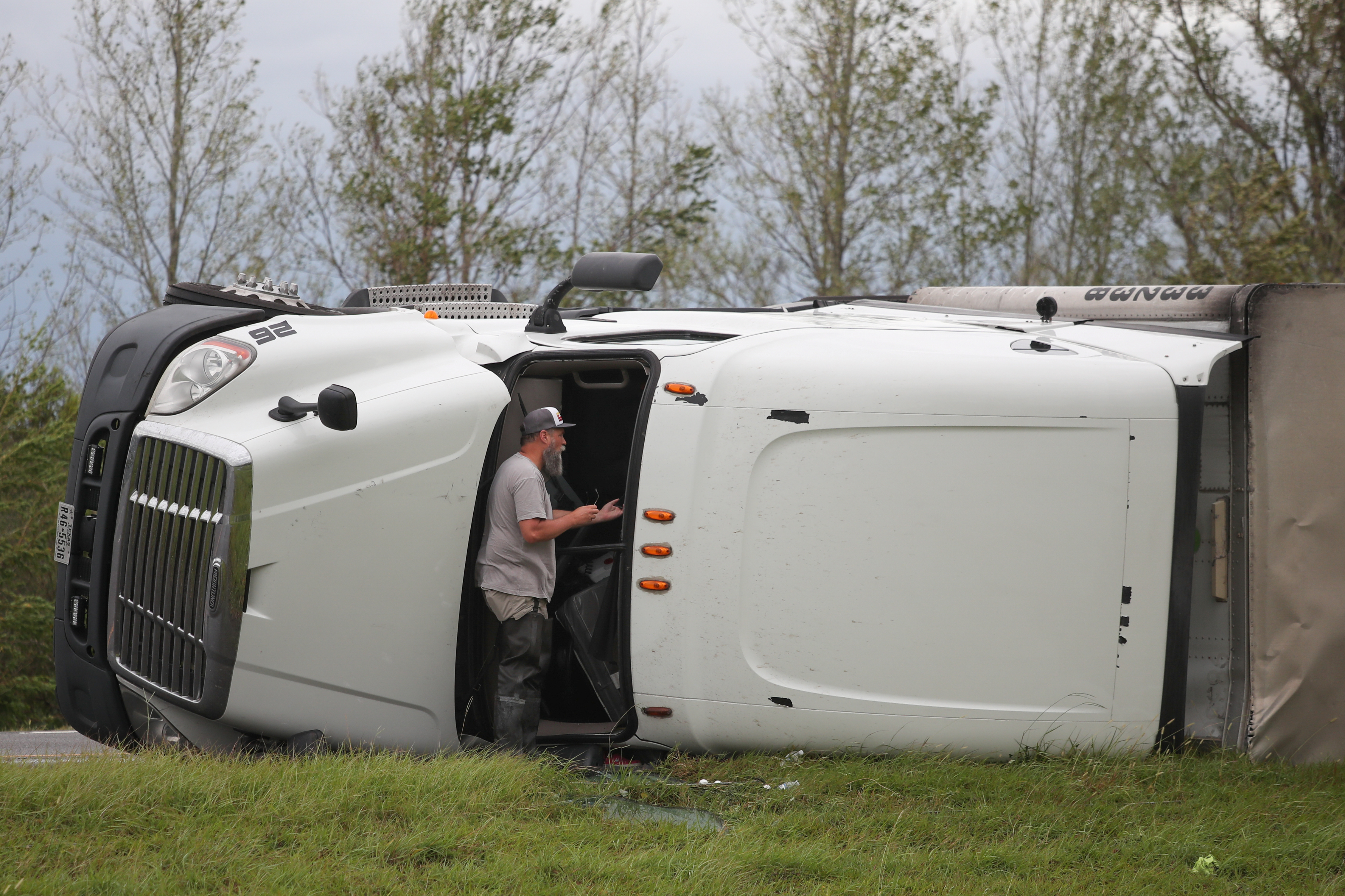 Un transeúnte habla con el conductor de un camión de 18 ruedas volcado después del huracán Laura en la I-10 en Vinton, Luisiana, el 27 de agosto de 2020 (REUTERS/Adrees Latif)