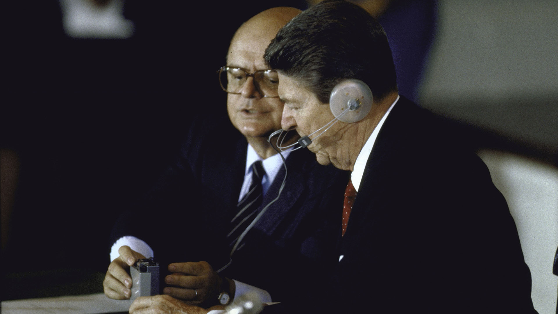  El presidente Ronald W. Reagan usando audífonos y recibiendo instrucciones del Secretario General de la OEA, Joao Clemente Baena Soares, sobre cómo usar su dispositivo de traducción durante una reunión de la OEA (Dirck Halstead/Getty Images)