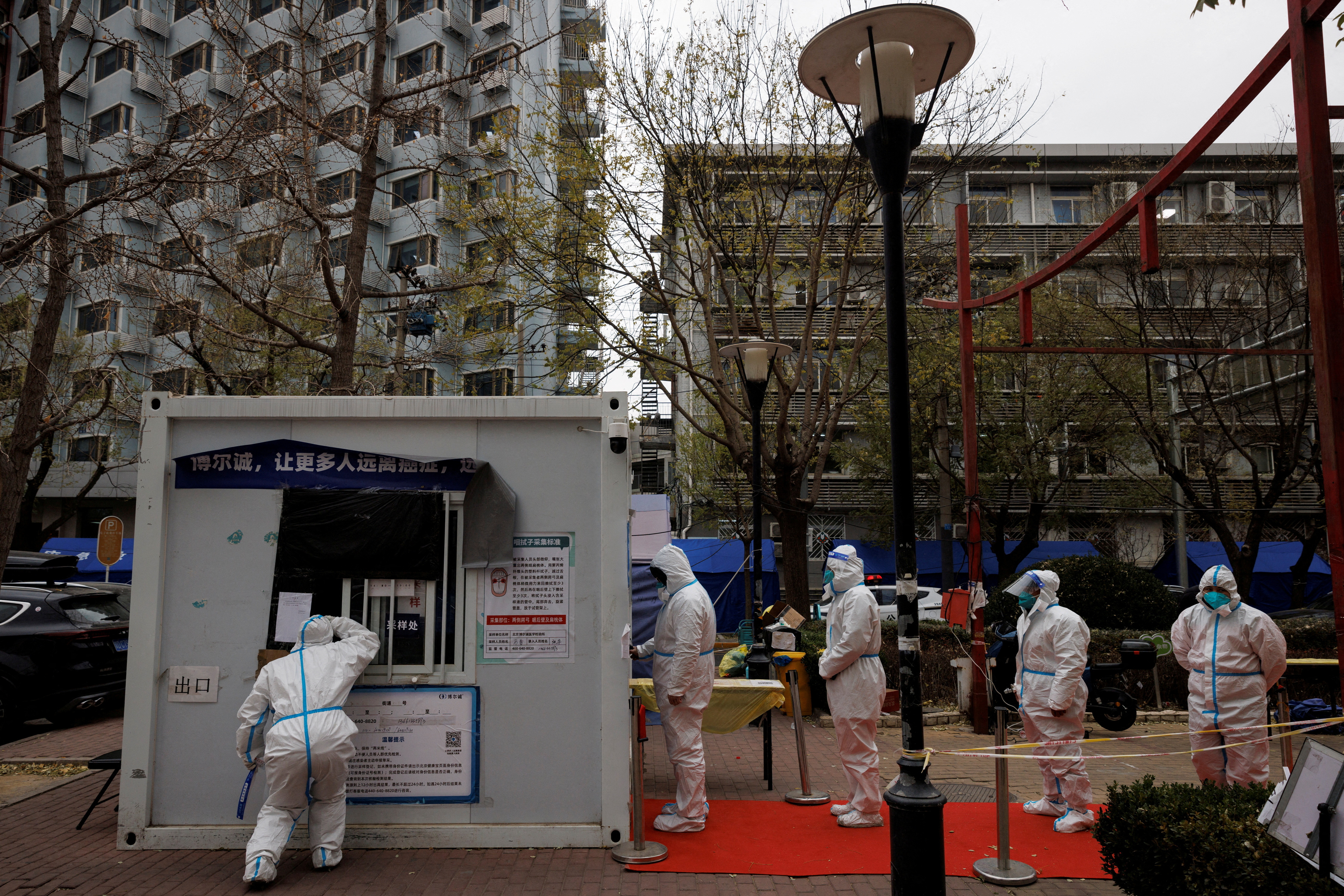 Trabajadores de prevención de epidemias con trajes protectores hacen fila para hacerse una prueba de hisopo mientras continúan los brotes de la enfermedad por coronavirus en Beijing (REUTERS/Thomas Peter)