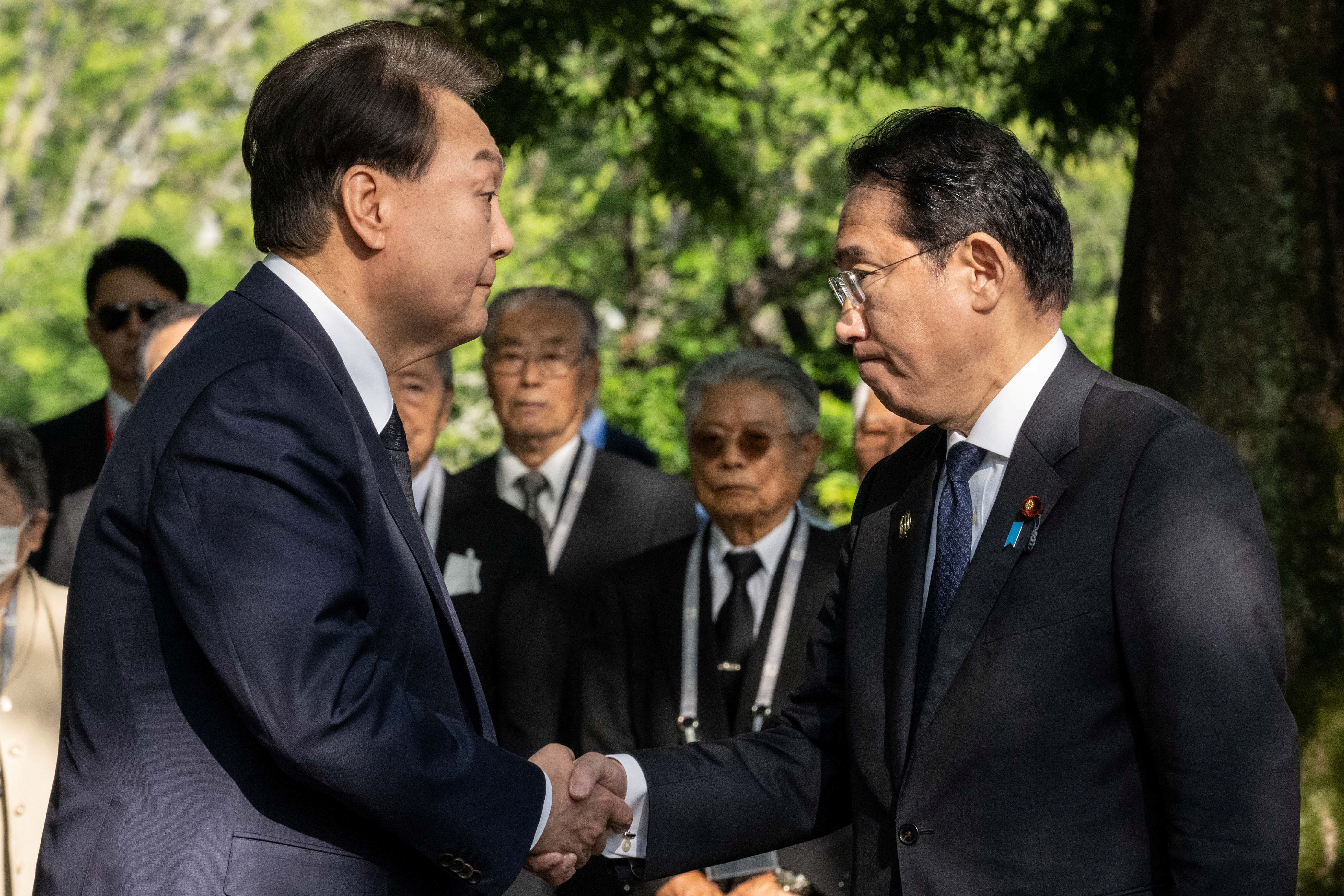 Yoon Suk Yeol de Corea del Sur y el primer ministro de Japón, Fumio Kishida, se dan la mano durante una visita al "Monumento en memoria de las víctimas coreanas de la bomba atómica", cerca del Monumento al Parque de la Paz en Hiroshima el 21 de mayo de 2023, al margen de la Reunión de Líderes de la Cumbre del G7. YUICHI YAMAZAKI/Piscina vía REUTERS
