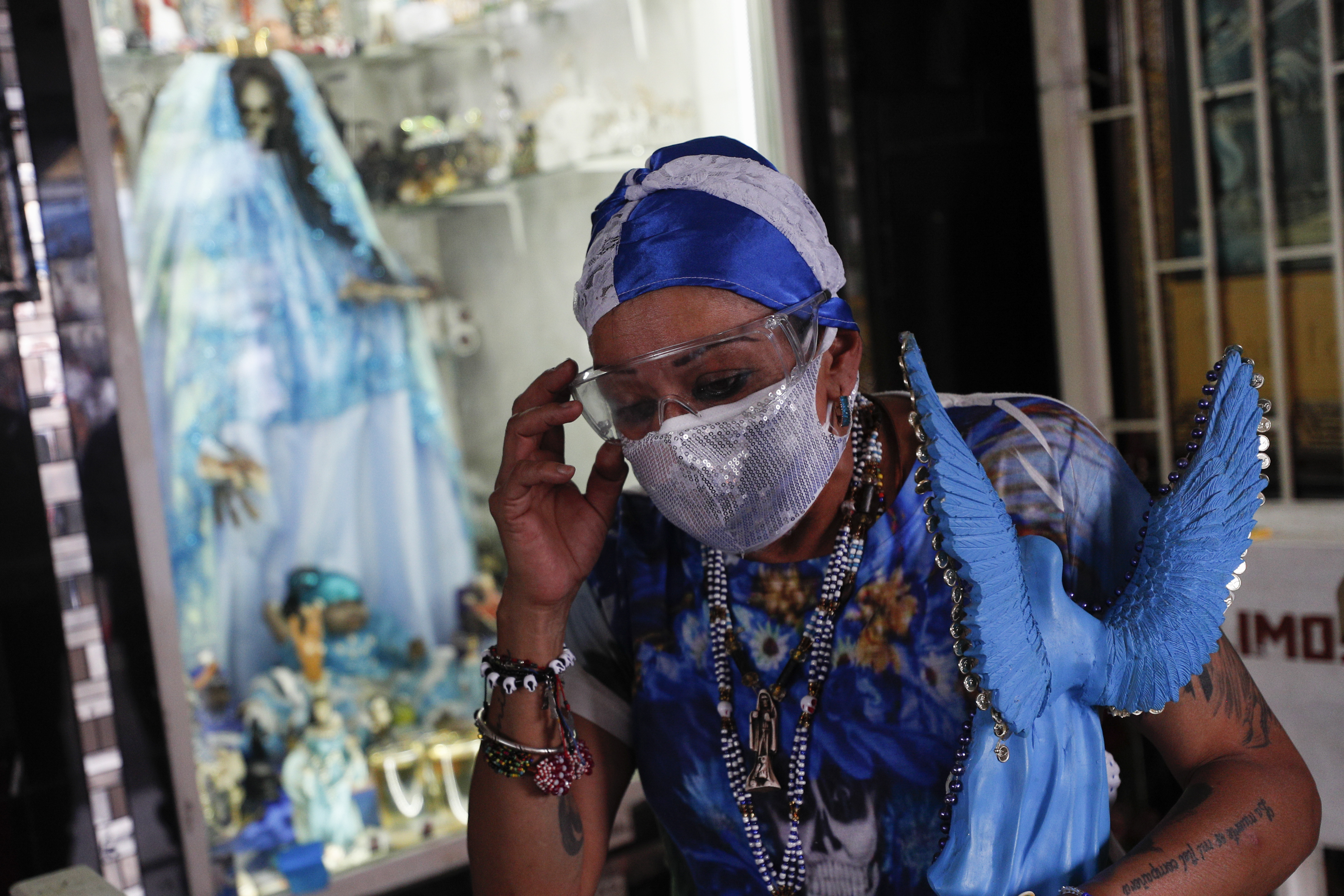 Una mujer se ajusta las gafas protectoras mientras se va después de visitar un altar a la Santa Muerte en el barrio de Tepito de la Ciudad de México, el lunes 1 de junio de 2020. (Foto AP / Rebecca Blackwell)