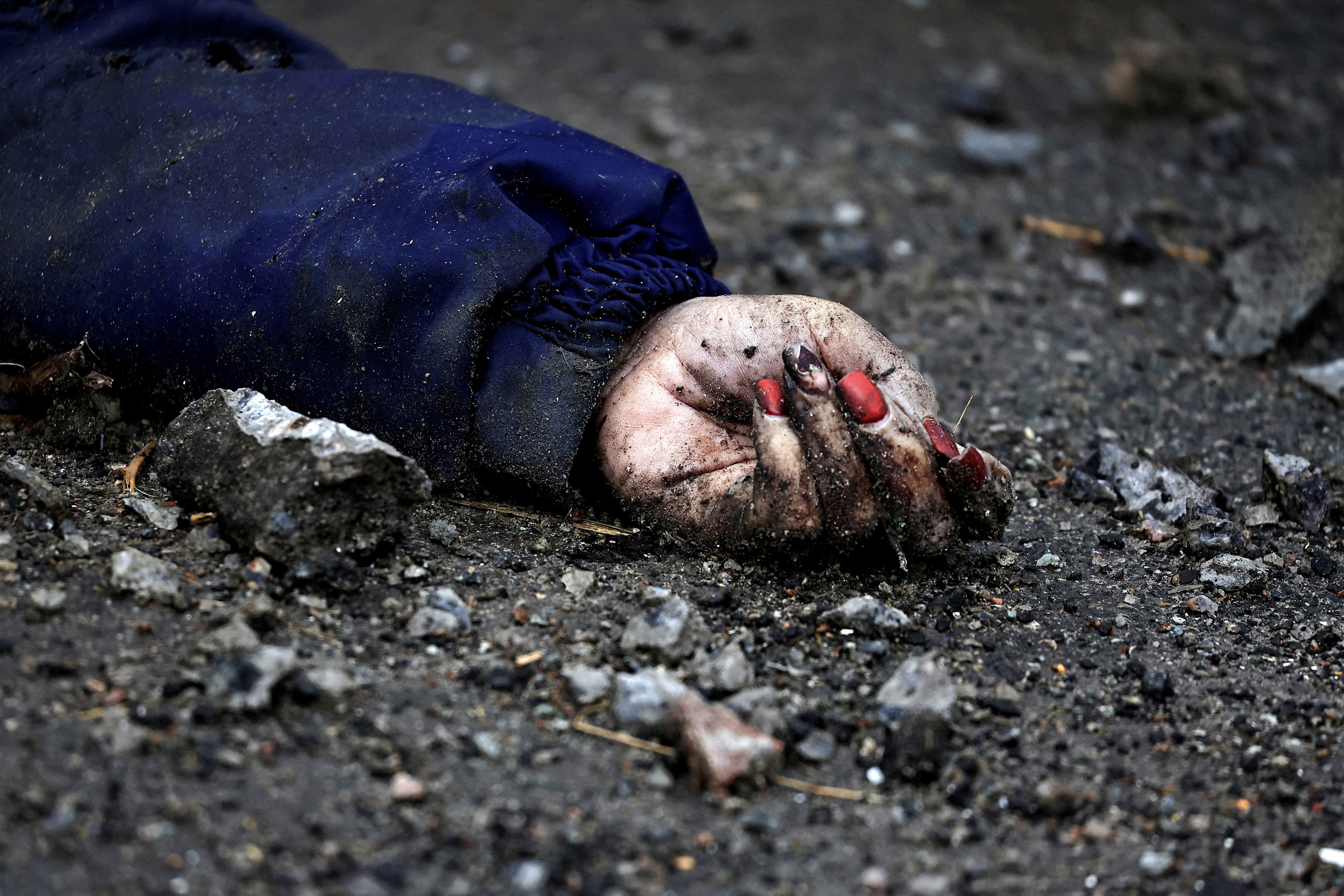 La mano de Iryna Filkina, una mujer que, según los residentes, fue asesinada por soldados del ejército ruso, es fotografiada mientras su cuerpo yace en la calle, en medio de la invasión rusa de Ucrania, en Bucha, región de Kyiv, Ucrania 2 de abril de 2022 (Reuters)