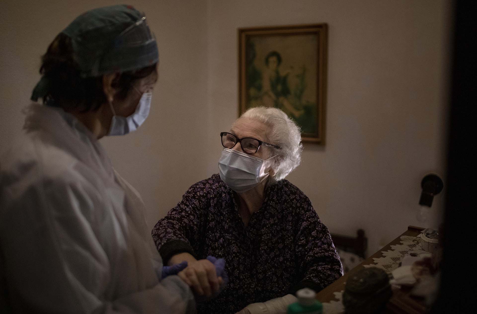 Pepita Jove Puiggros, de 92 años, sostiene la mano de una enfermera durante una visita en Barcelona, España (AP Photo/Emilio Morenatti)