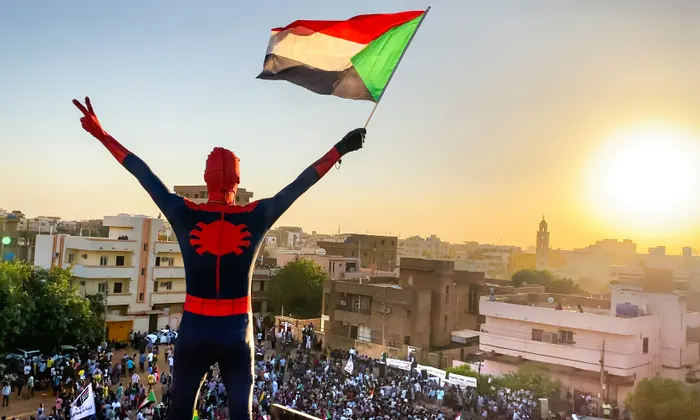 "Spidey", como le dicen los manifestantes, enarbola una bandera de Sudán en medio de una protesta. Foto: The Guardian