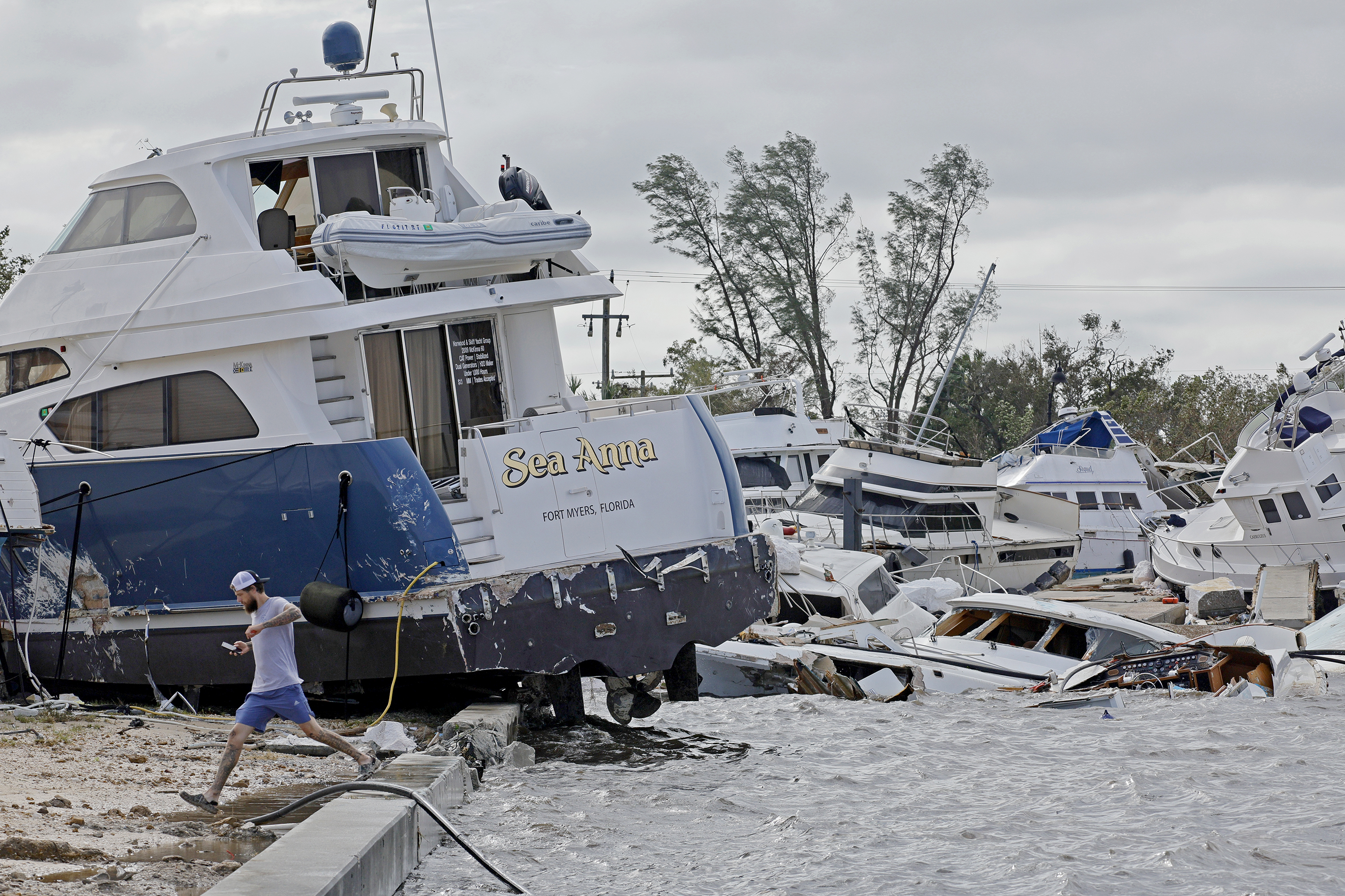 Joe Dalton, de vacaciones desde Cleveland, Ohio, revisa los botes varados en Fort Myers Wharf, a lo largo del río Caloosahatchee, el jueves 29 de septiembre de 2022 en Fort Myers, Florida, luego del huracán Ian. (Amy Beth Bennett/South Florida Sun-Sentinel via AP)