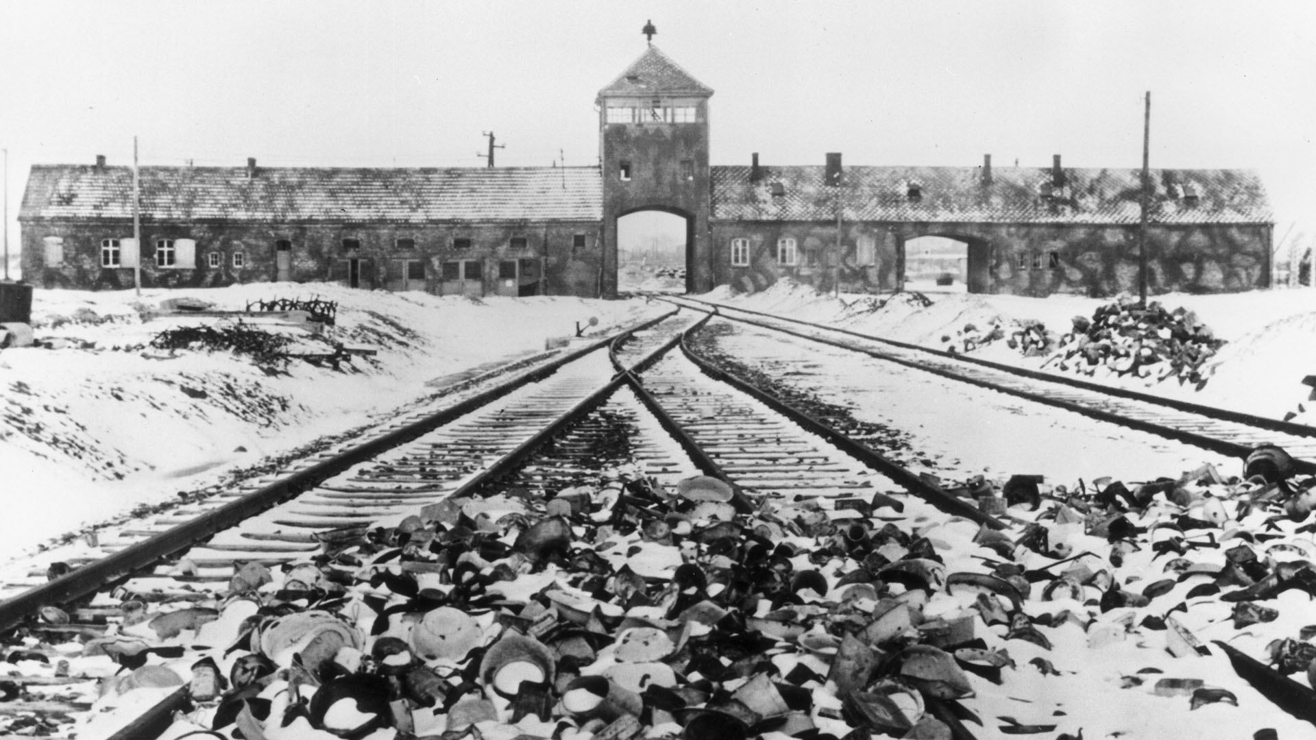 Una postal de 1945. Los efectos personales cubiertos de nieve de los deportados al campo de concentración de Auschwitz ensucian las vías del tren que conducen a la entrada del campo (Hulton Archive/Getty Images)