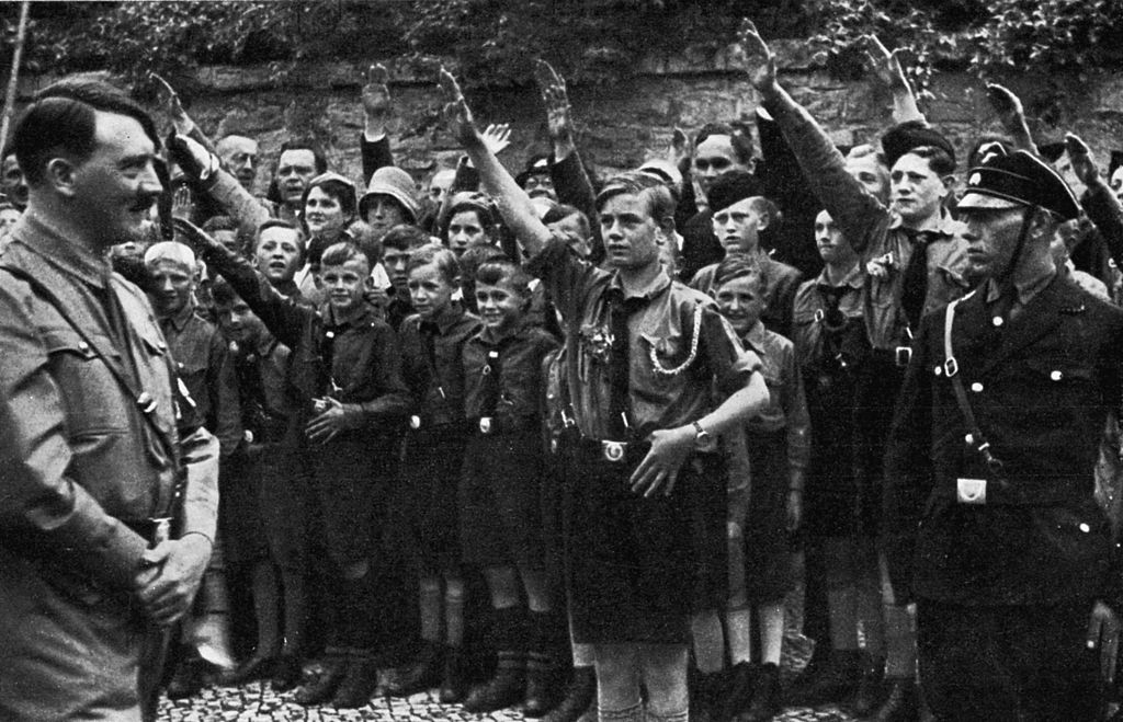1933:  Nazi leader Adolf Hitler smiles while uniformed Saxon youths salute him outdoors in Erfurt, Germany.  (Photo by Hulton Archive/Getty Images)
