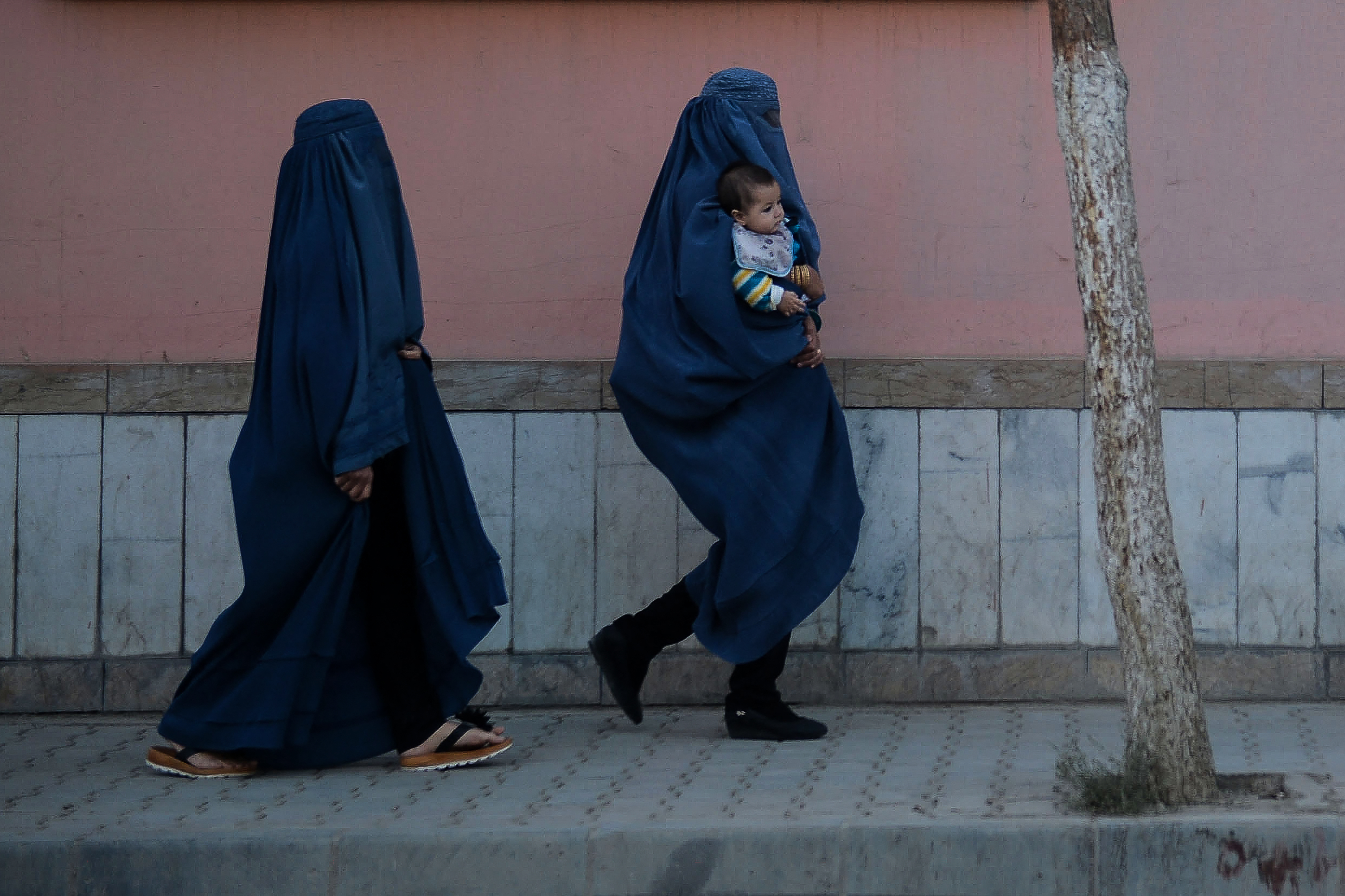 Una mujer camina por Kabul con un bebé en brazos. No se puede saber la edad de la madre porque el burka cubre todo su cuerpo. (Photo by Hoshang Hashimi / AFP)