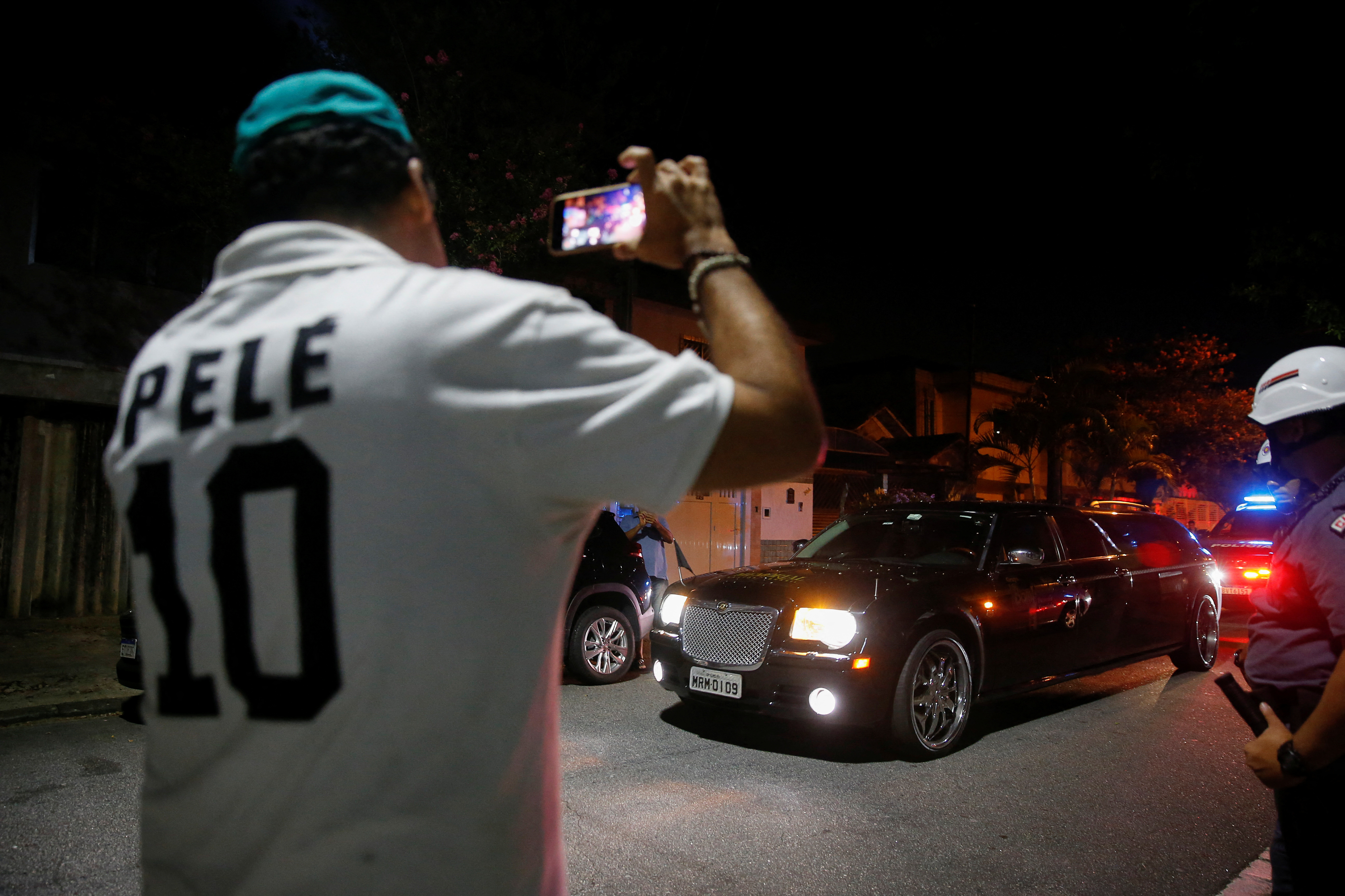 Un fanático toma una foto del auto que lleva el cuerpo de Pelé (REUTERS/Diego Vara)