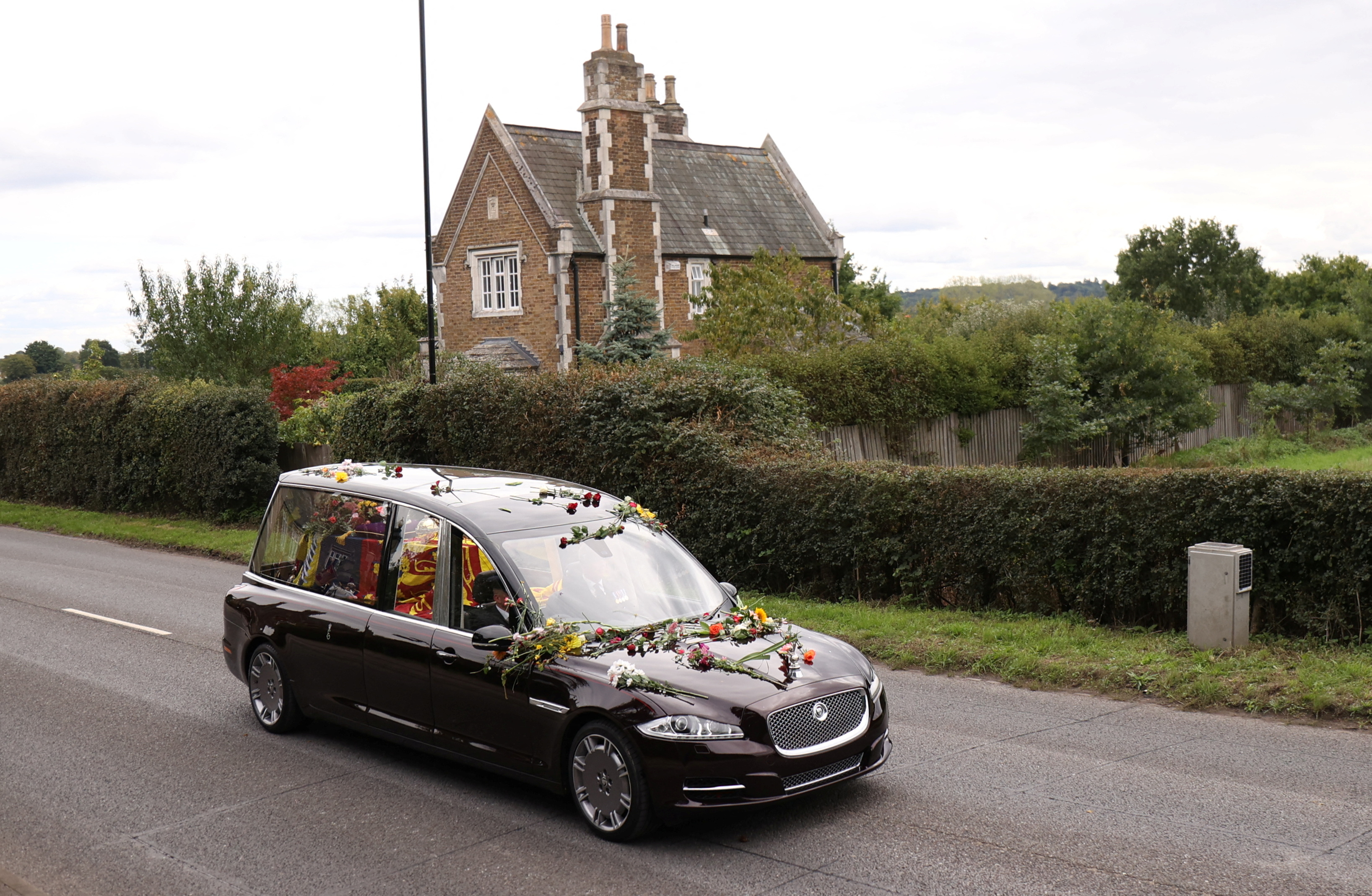 El auto transporta el ataúd de la reina Isabel de Gran Bretaña lleno de flores, conducen a lo largo de Albert Road. 