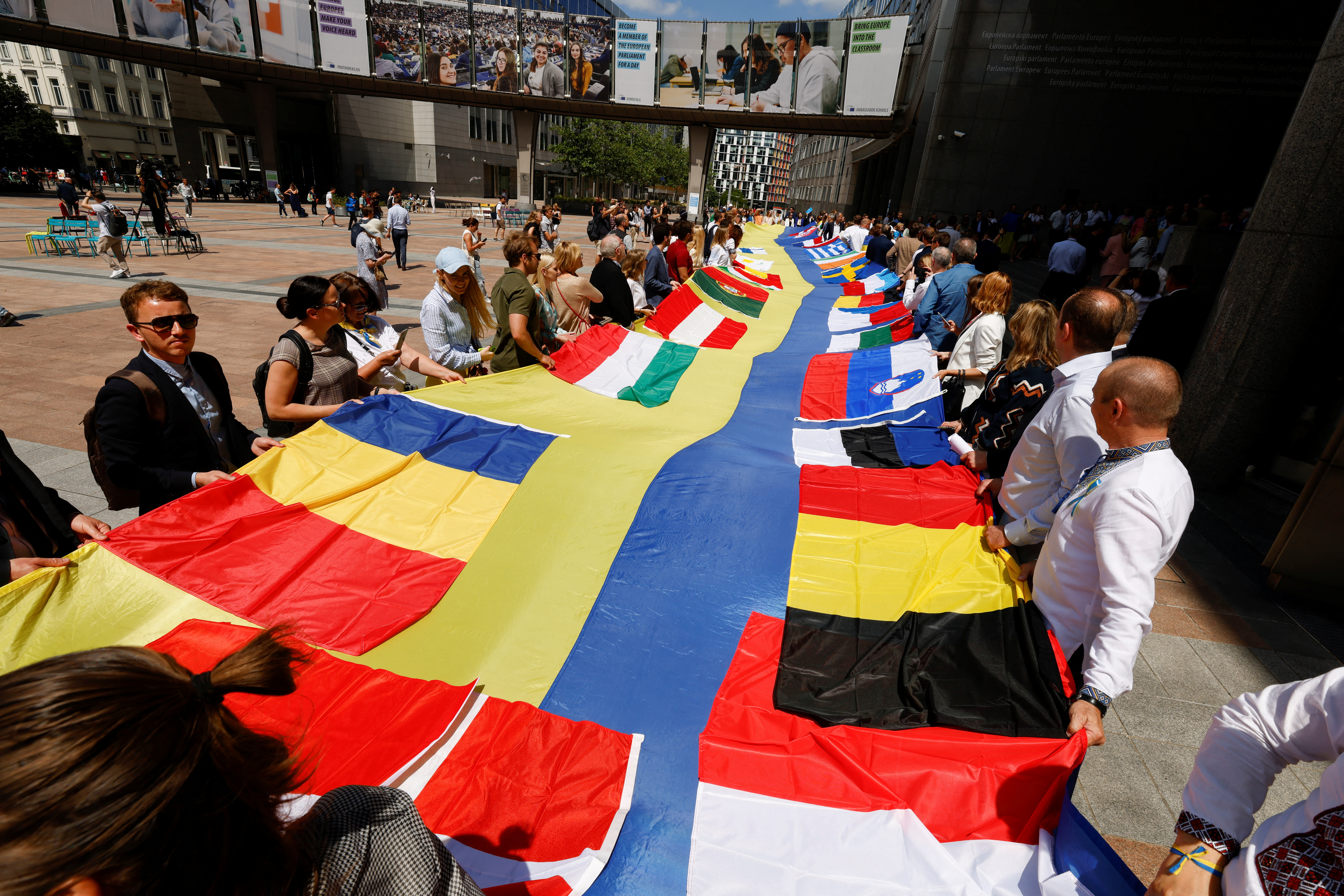 Un grupo de manifestantes en Bruselas con una bandera ucraniana de 30 metros de largo adornada con las insignias de los países miembros de la Unión Europea. REUTERS/Yves Herman