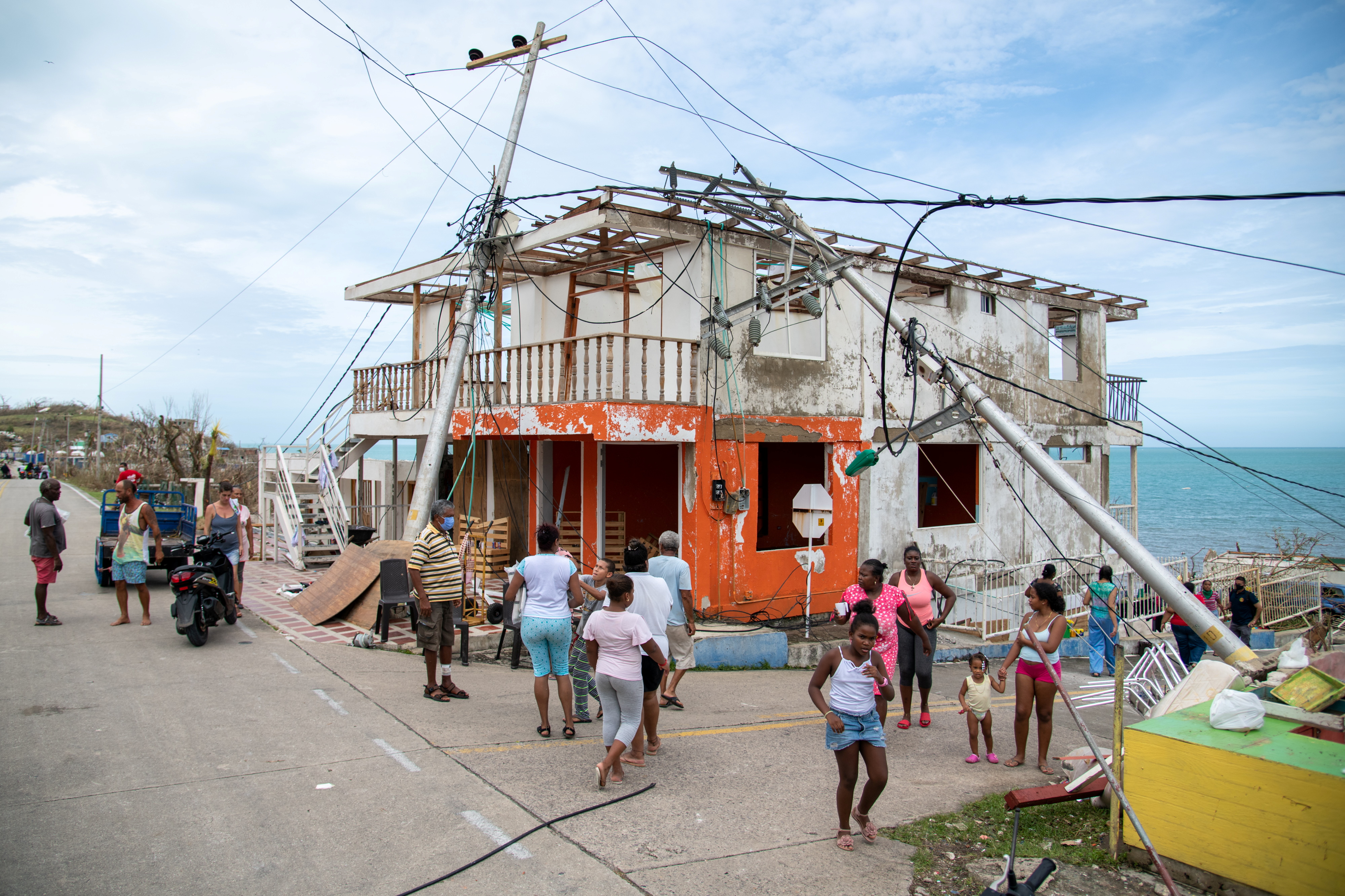 People walk near a damaged house and fallen electricity poles after the passing of Storm Iota, in Providencia, Colombia November 17, 2020. Picture taken November 17, 2020. Efrain Herrera/Colombia Presidency/Handout via REUTERS   ATTENTION EDITORS - THIS IMAGE HAS BEEN SUPPLIED BY A THIRD PARTY. NO RESALES. NO ARCHIVES.