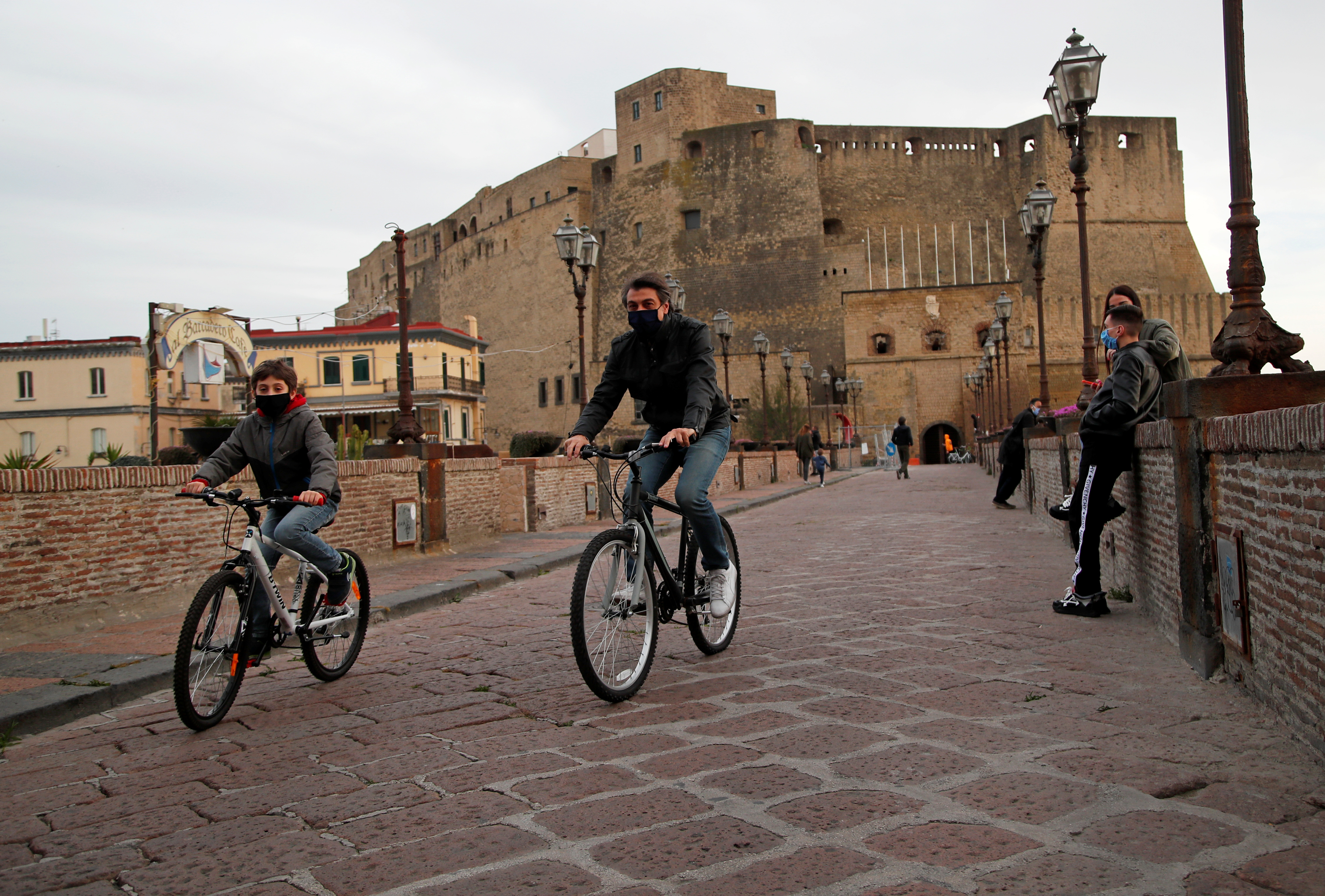 Una familia circula en bicicleta por Nápoles, todos con mascarillas (Reuters)